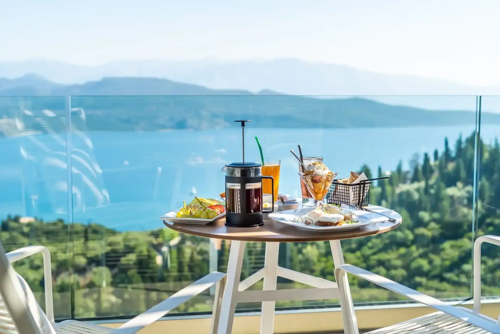 Gedeckter Tisch mit Kaffee und Frühstück auf dem Balkon mit Blick auf das blaue Meer.