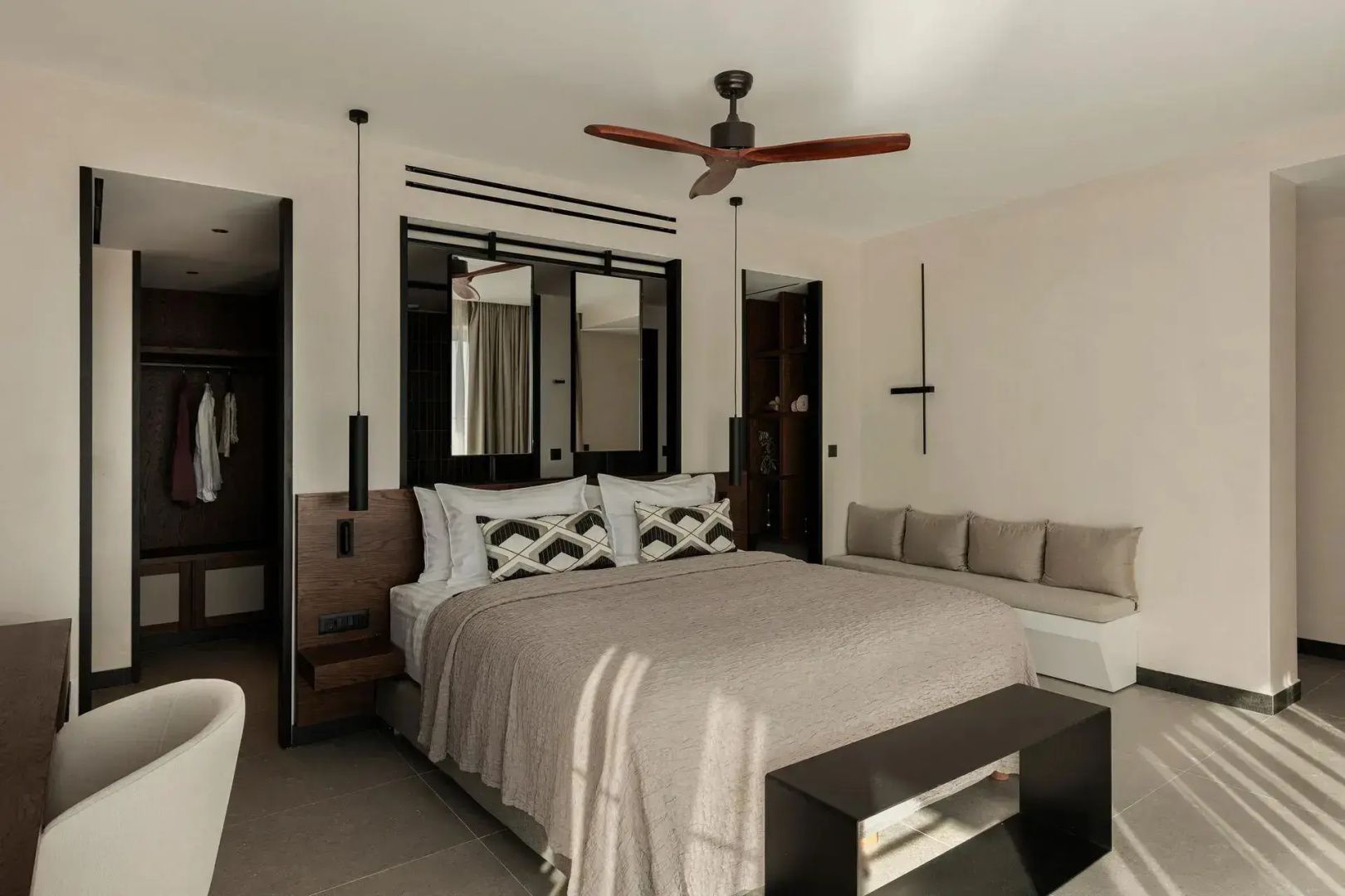 Schlafzimmer mit Doppelbett, Deckenventilator aus Holz und hellen Wänden.
