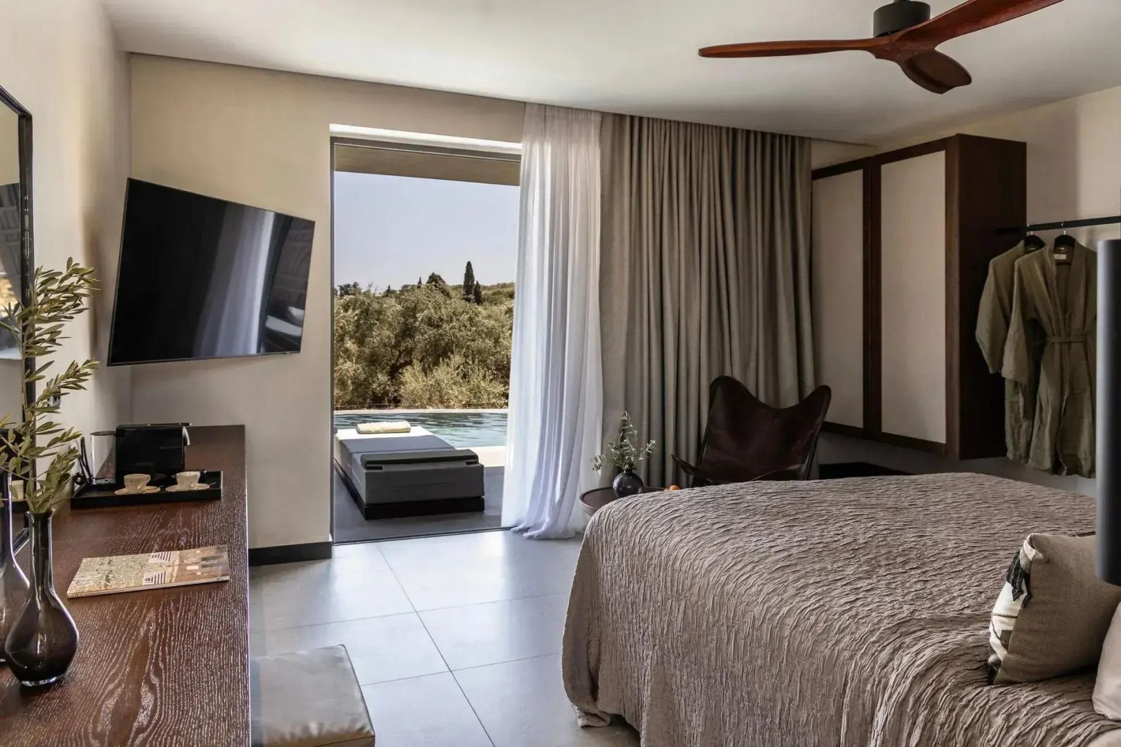 Modernes Hotelzimmer mit Doppelbett, Flachbild-TV und einer Terrasse mit eigenem Pool und Baumblick.