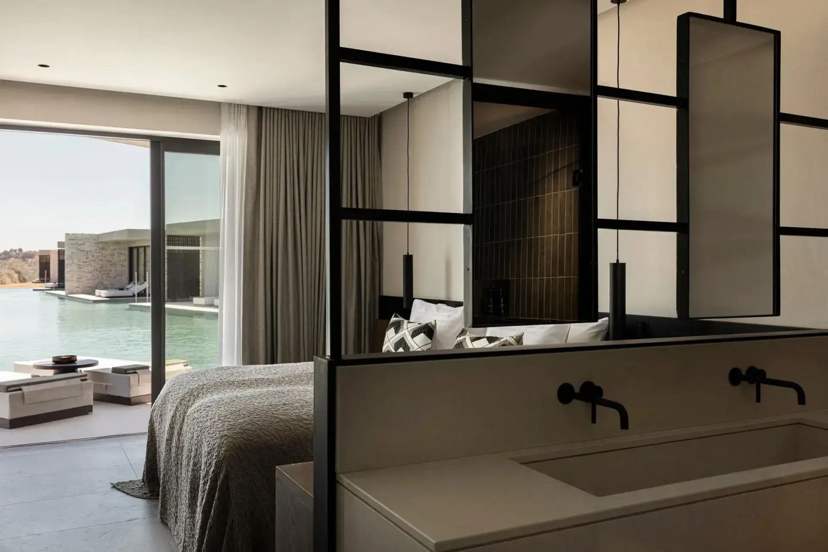 Offenes Hotelzimmer mit Waschtisch im Vordergrund und einem Doppelbett dahinter.
