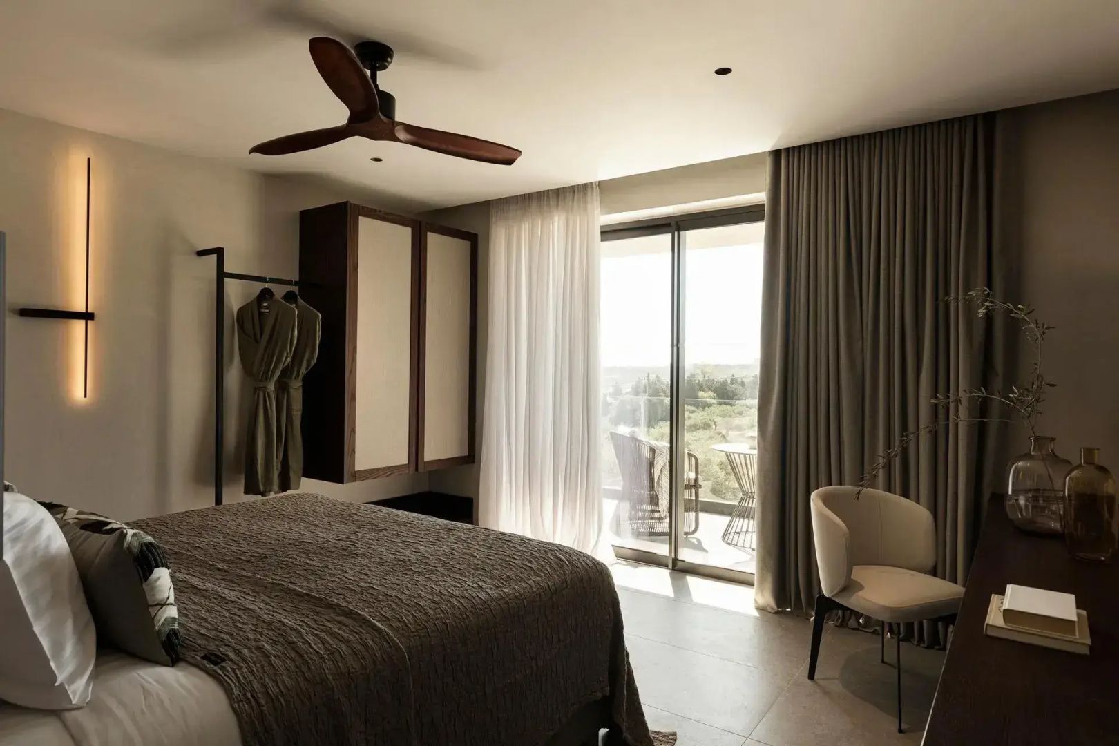 Modernes Hotelzimmer mit Doppelbett, Deckenventilator und Zugang zum Balkon.