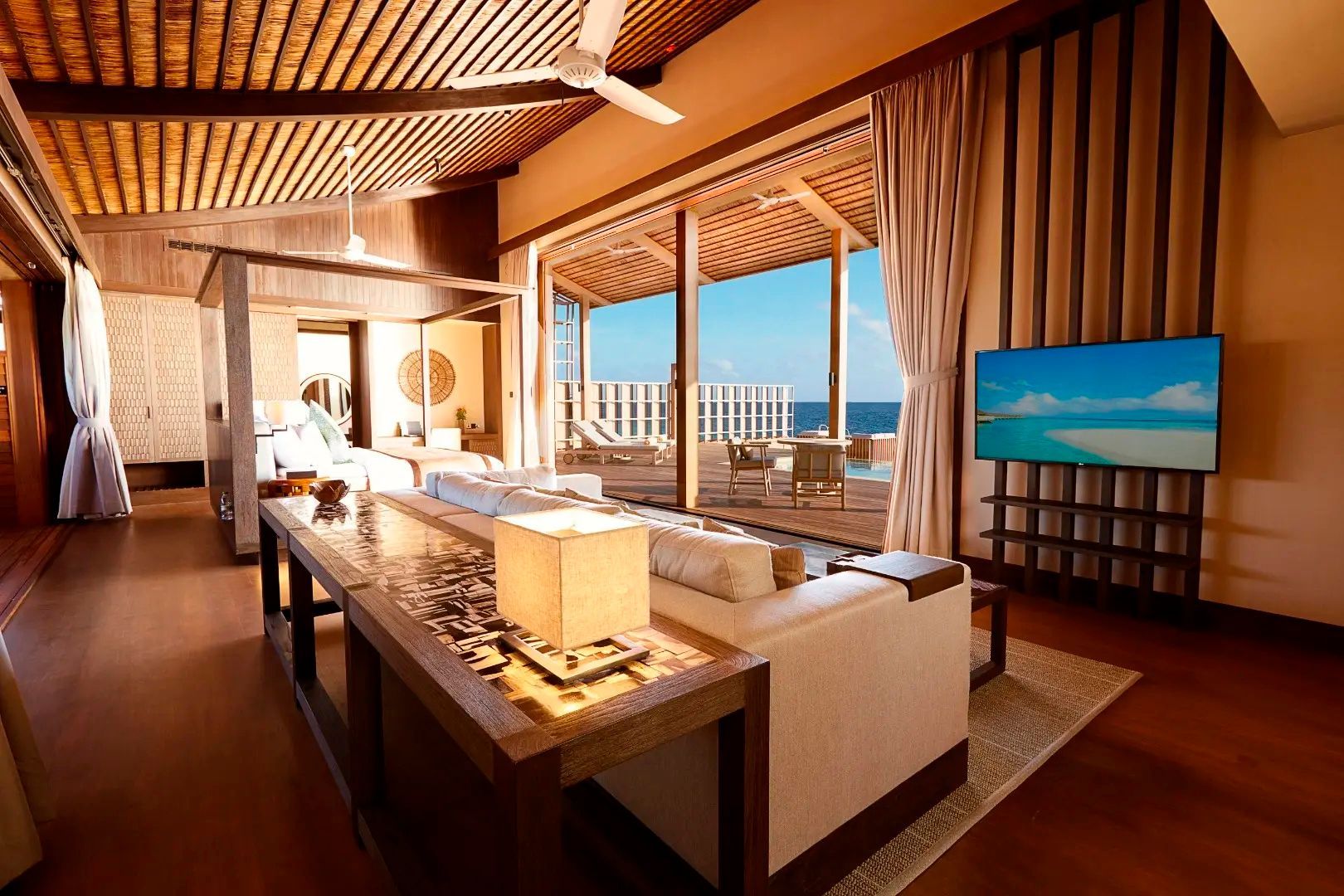 Offener Wohnbereich mit Sofa, Fernseher und Blick auf die Terrasse und das Meer.