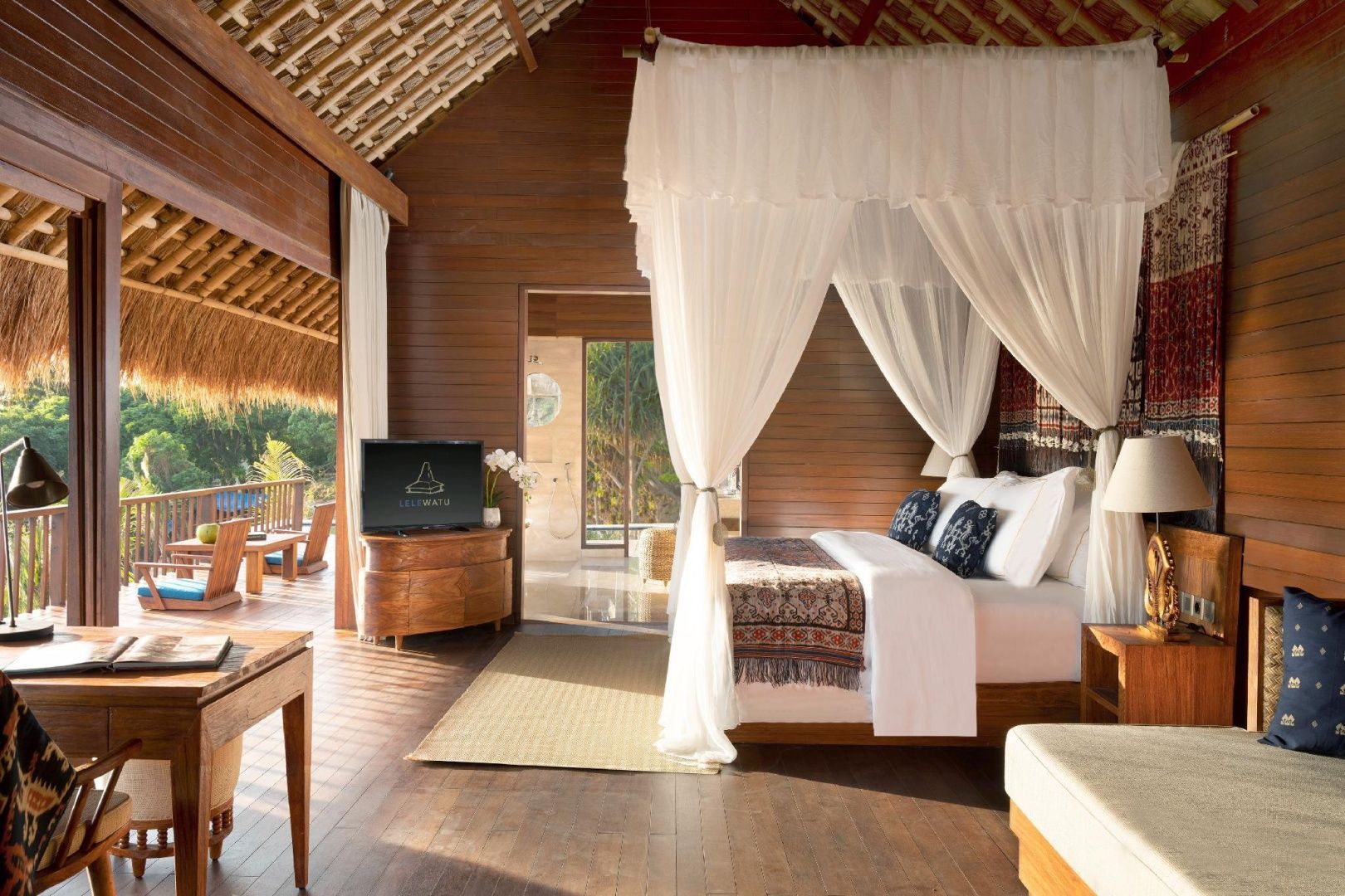 Helles Schlafzimmer in einer Holzvilla mit Himmelbett, Holzmöbeln und Blick nach draußen.