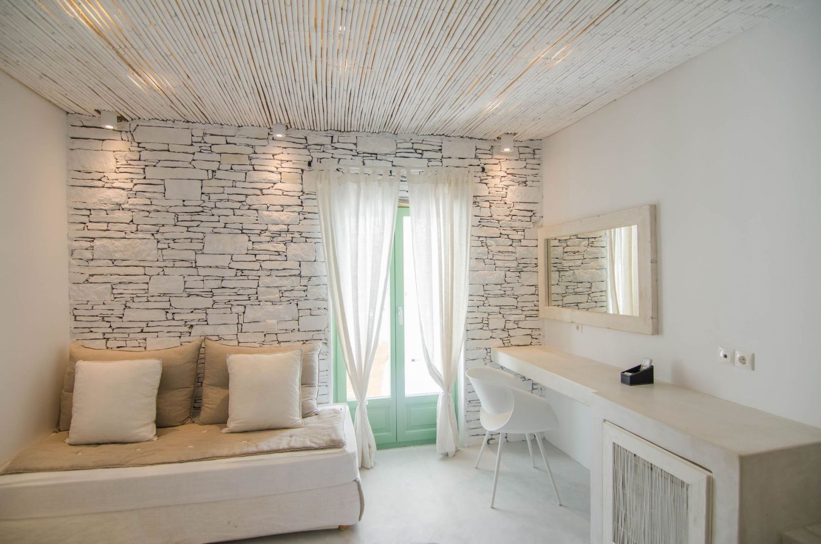 Wohnbereich im Zimmer mit Sofa, Schreibtisch und Natursteinwand.
