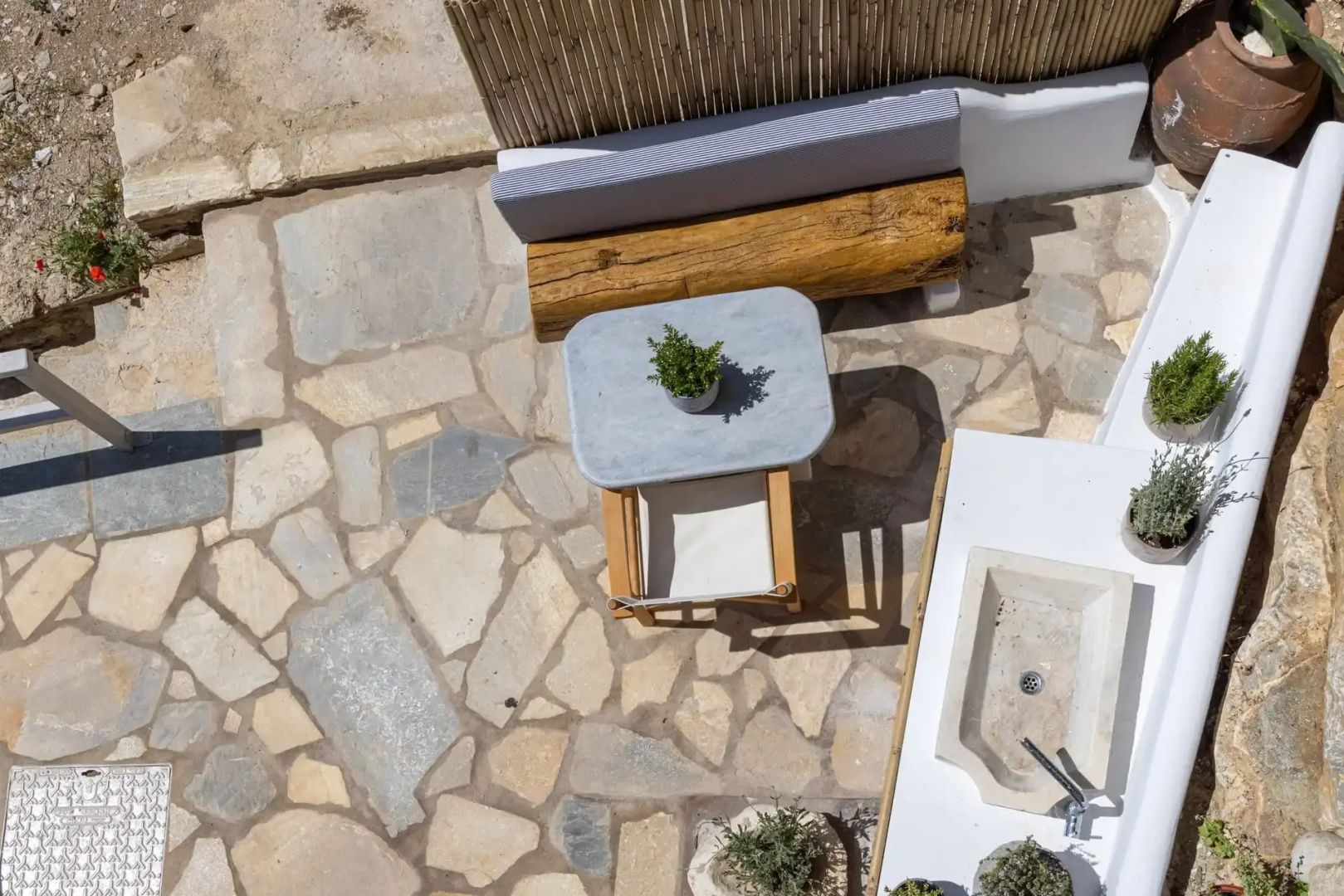 Blick von oben auf eine Terrasse mit Steintisch, Stuhl und Holzelementen.