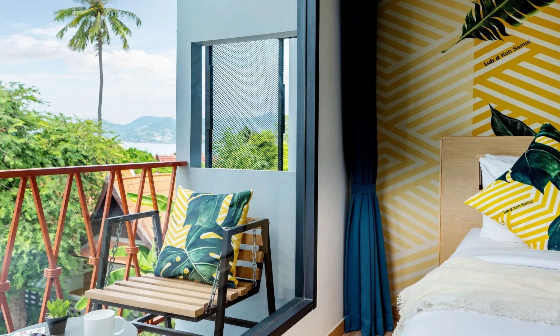 Blick vom Zimmer auf einen Stuhl auf dem Balkon mit Meeres- und Landschaftsaussicht.