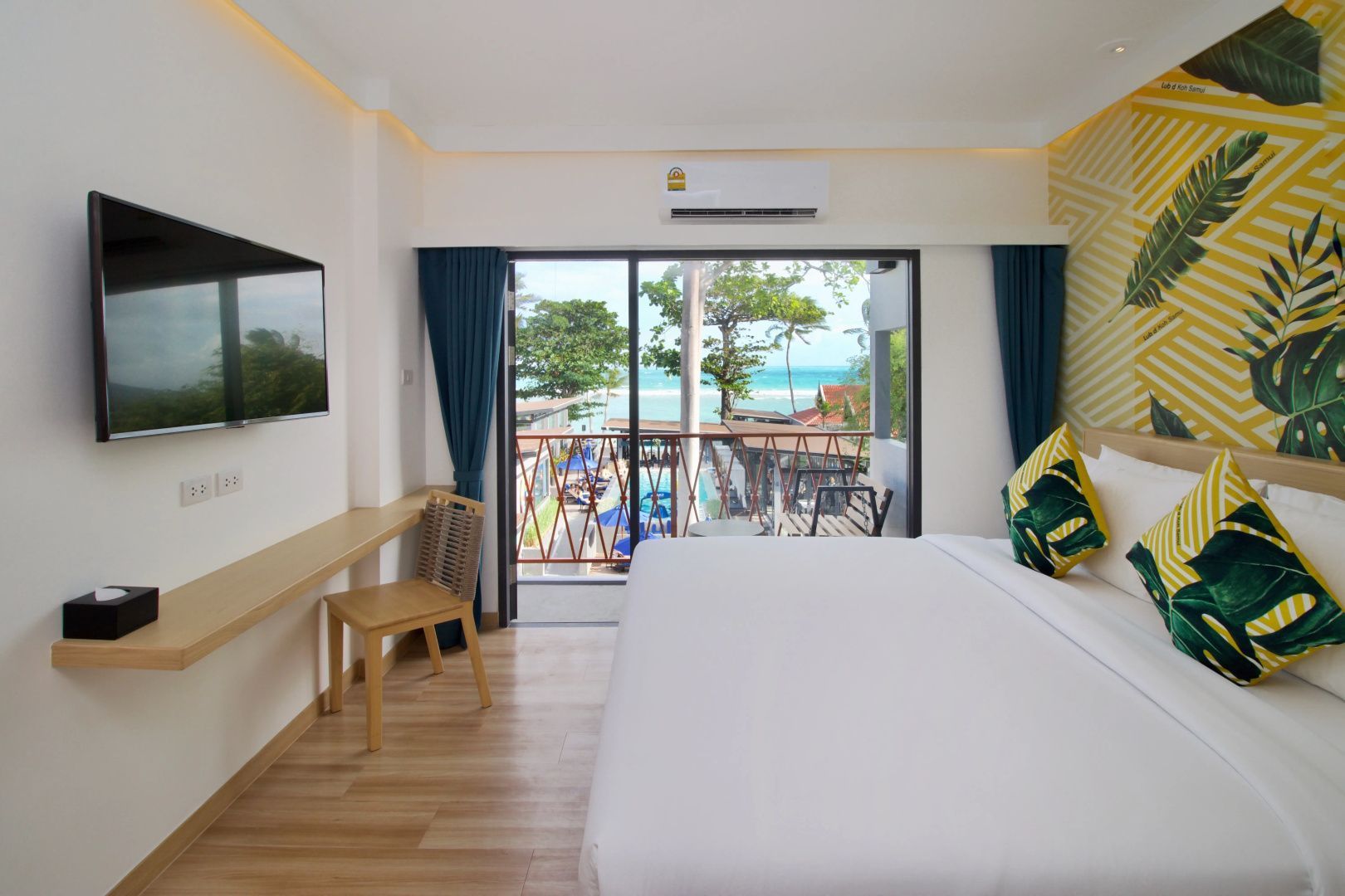 Doppelzimmer mit großem Holzfußboden, Fernseher und Balkon mit Blick auf das Meer.