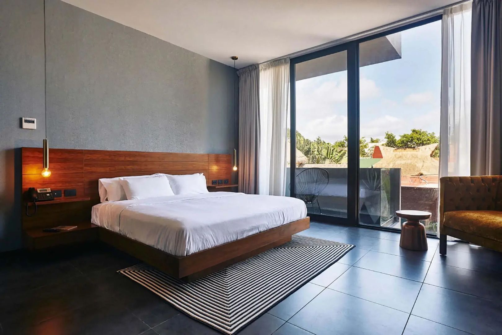Modernes Hotelzimmer mit Doppelbett, Kopfteil aus Holz und großer Fensterfront.