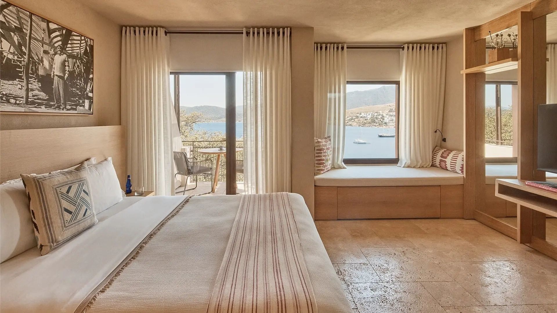 Blick aus einem Hotelzimmer über eine Sitznische auf eine Bucht mit Booten.
