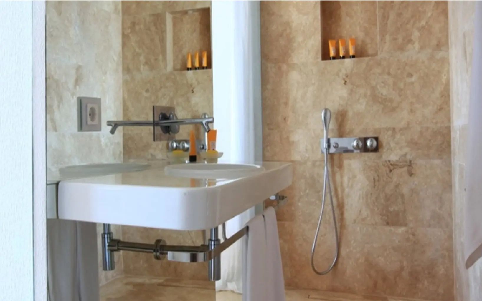 Badezimmer mit Waschbecken aus Stein, Spiegelfläche und Armaturen.