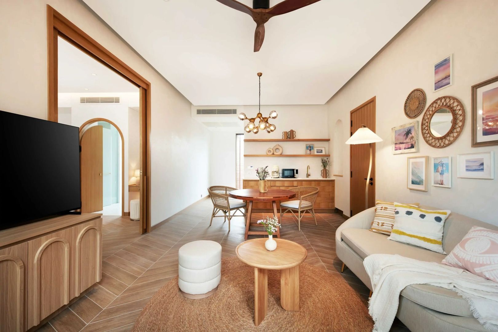 Wohnbereich mit hellem Sofa, Couchtisch, rundem Teppich, Esstisch und Deckenventilator.