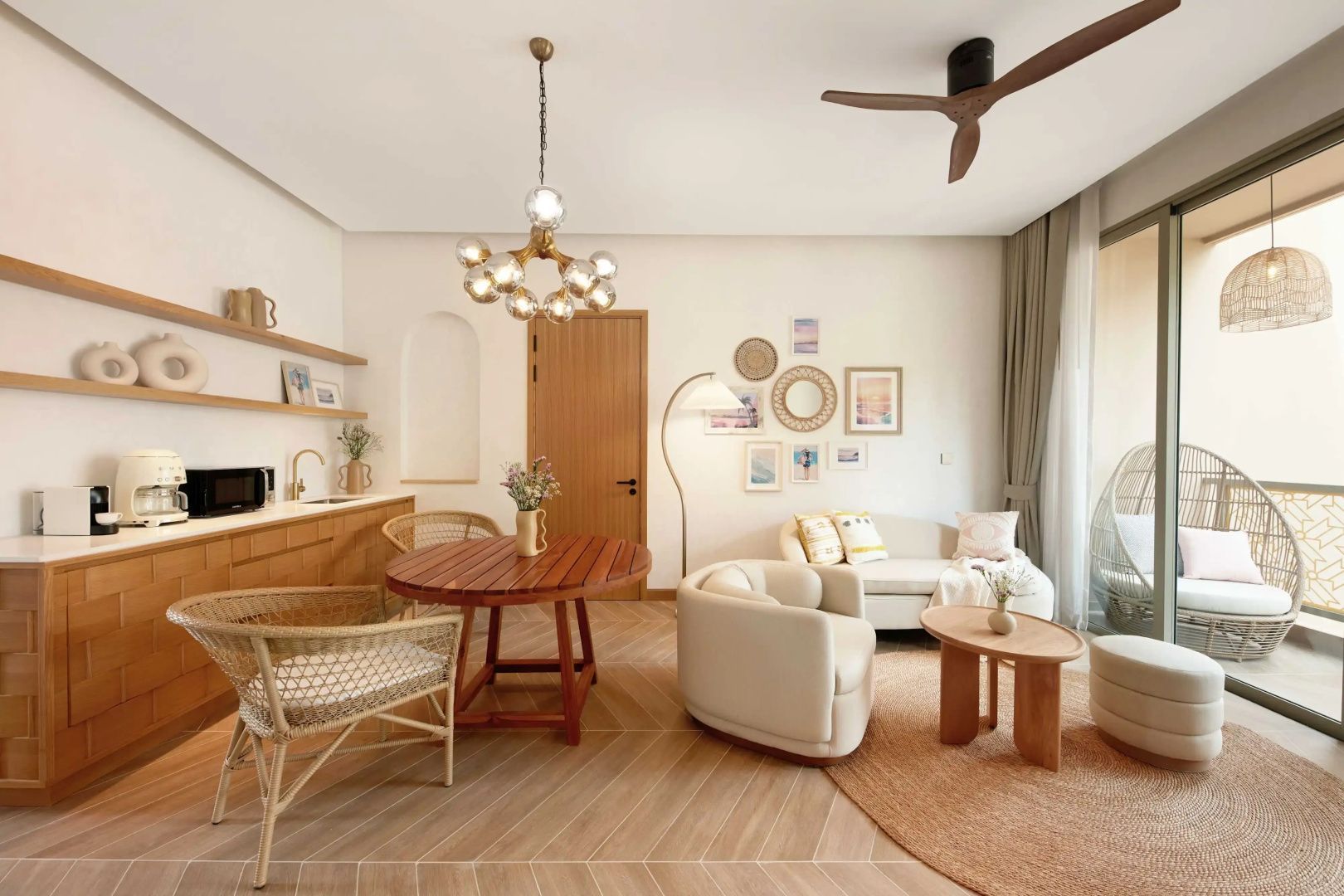 Wohnzimmer mit hellem Sofa, Sesseln, Wanddekoration und runder Essgruppe auf Fliesenboden.