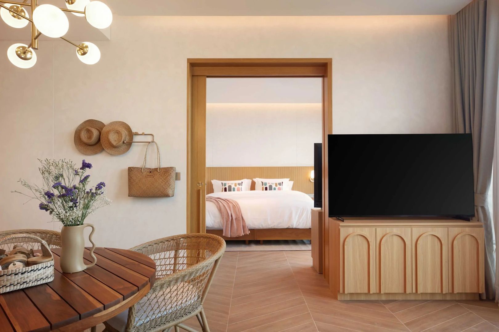 Wohnbereich mit Holztisch und Stuhl mit Blick durch die Tür ins Schlafzimmer.