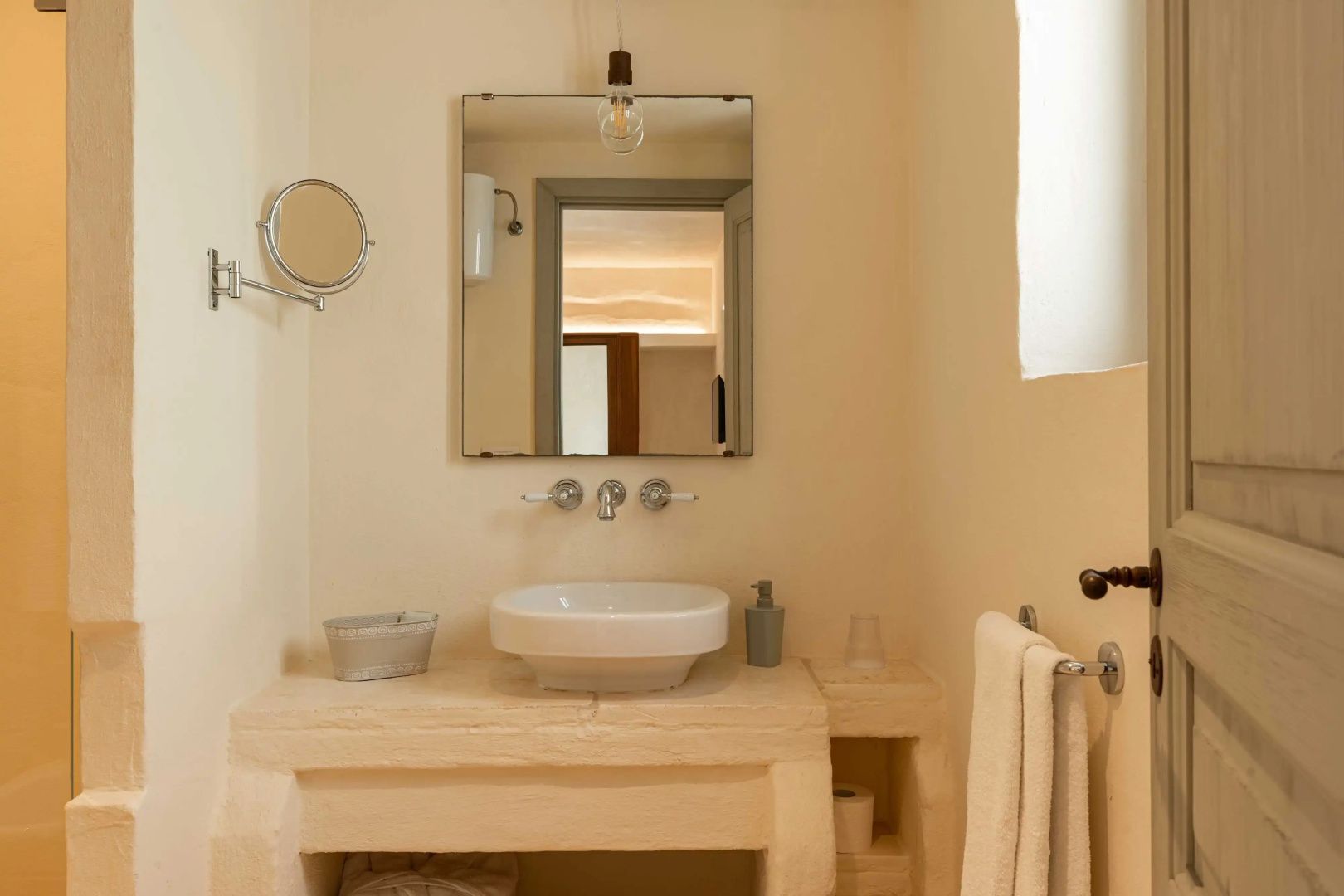 Badezimmer mit Steinwaschtisch, rechteckigem Spiegel und hellen Wänden.