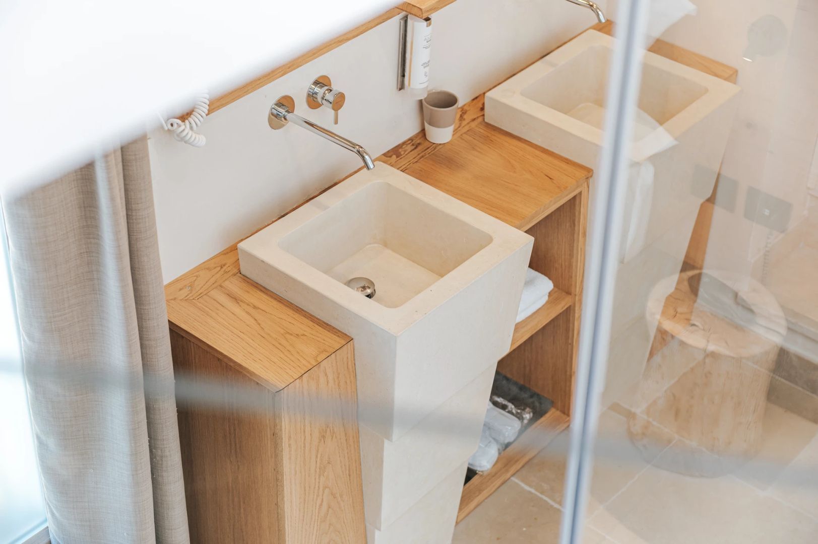 Eckiger Steinwaschtisch auf einer Holzkommode im Badezimmer des Hotels.