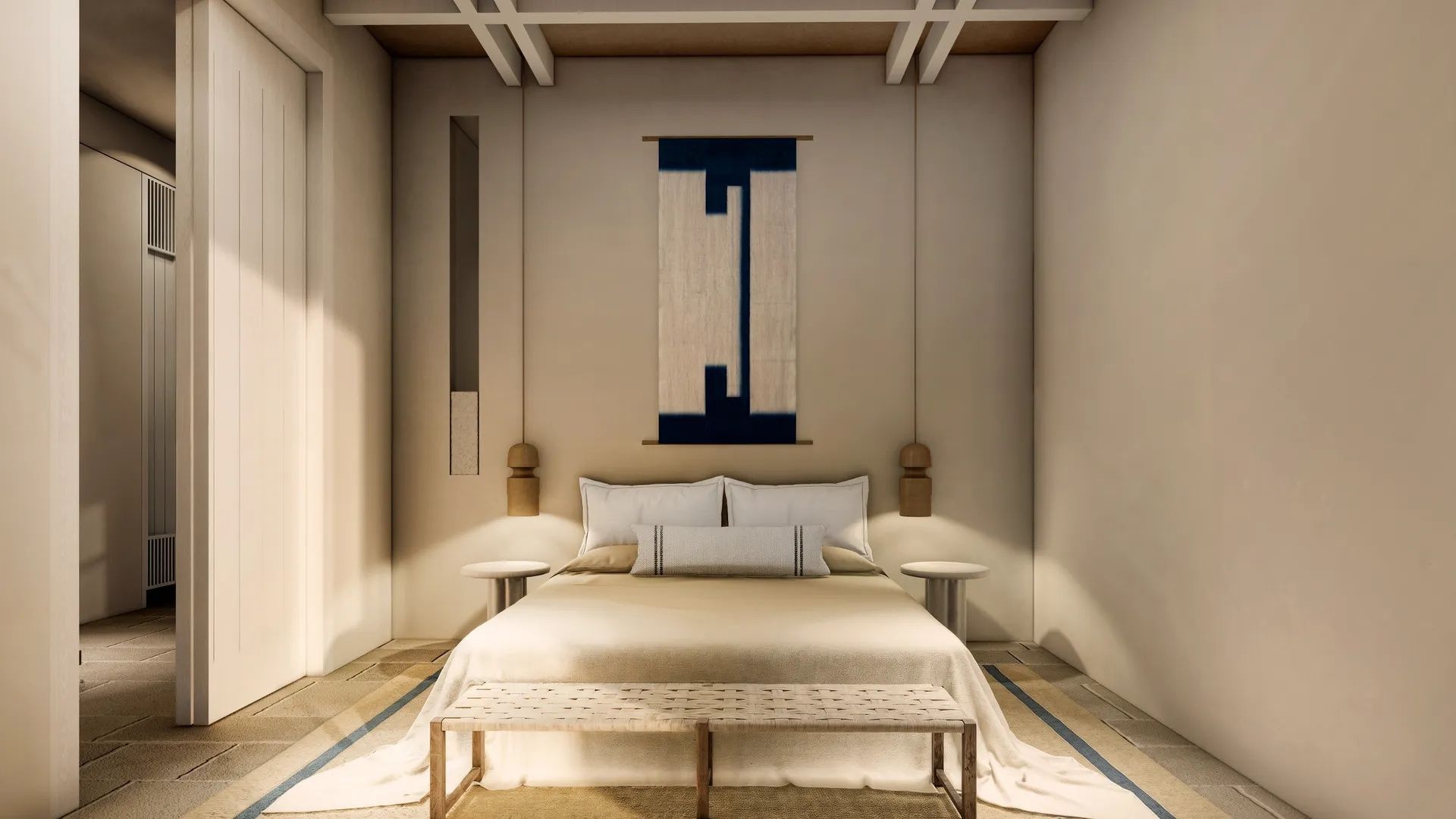 Doppelbett mit hellen Kissen, einer Sitzbank und einem Wandteppich im Zimmer.