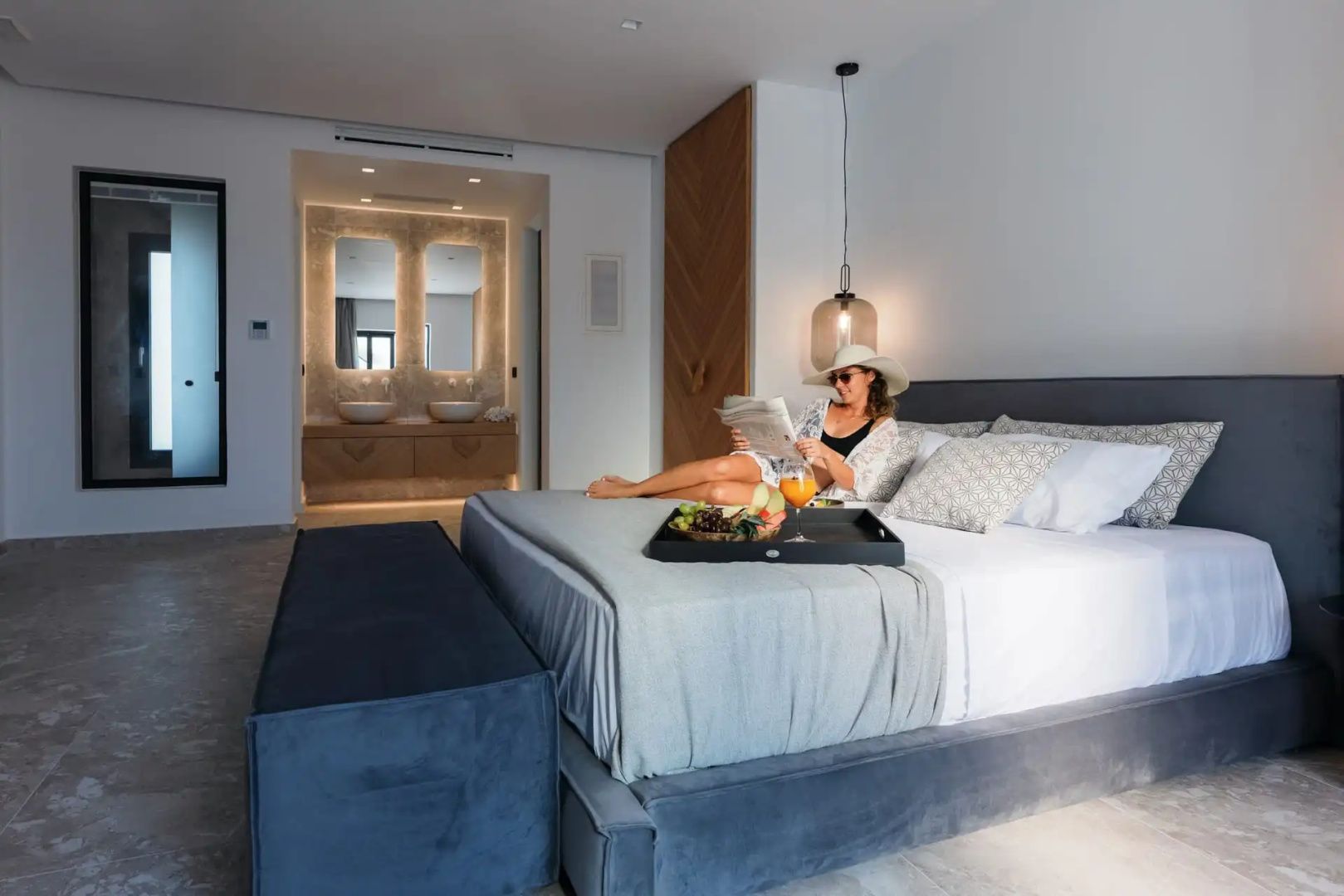 Schlafzimmer mit Doppelbett und Blick auf den integrierten Waschtischbereich im Hintergrund.