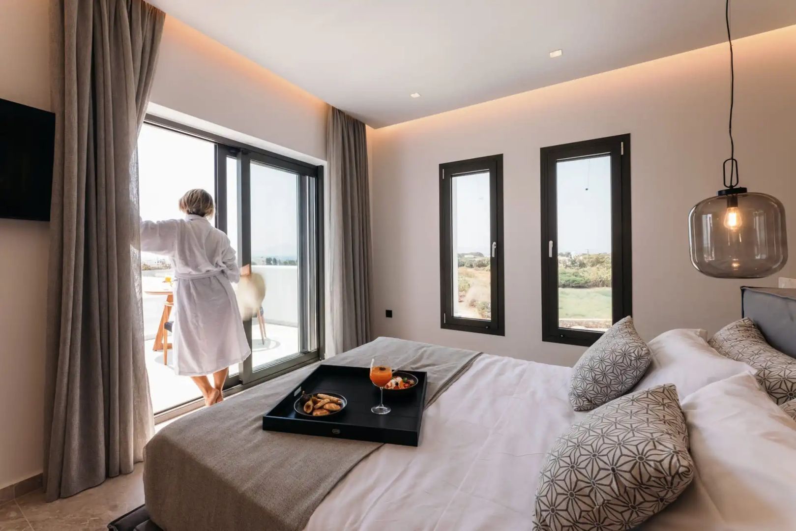 Blick aus dem Schlafzimmer auf die Terrasse mit stehender Person im Bademantel.