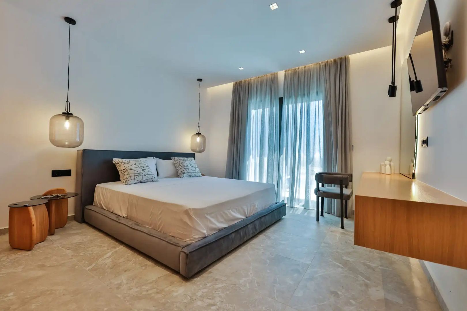 Modernes Schlafzimmer mit Doppelbett, getönten Pendelleuchten und bodentiefen Vorhängen.