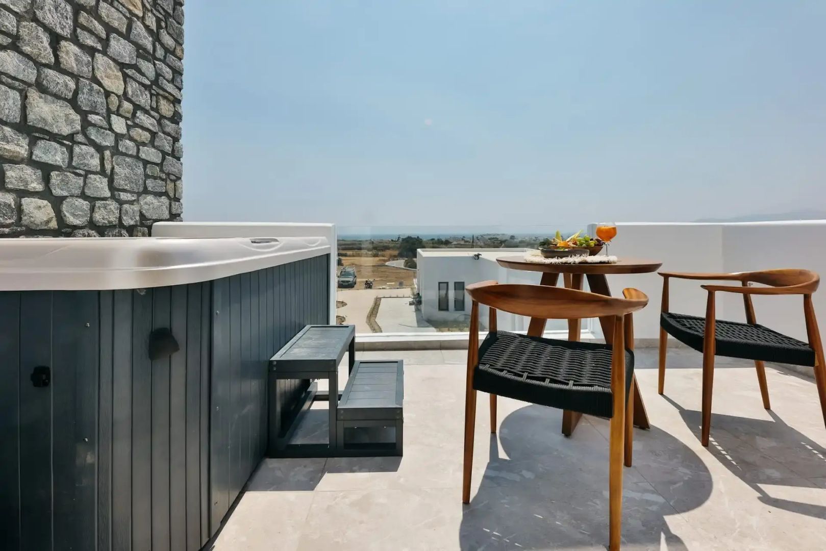 Balkon mit Whirlpool sowie Holztisch und Stühlen mit freiem Blick auf die Landschaft.