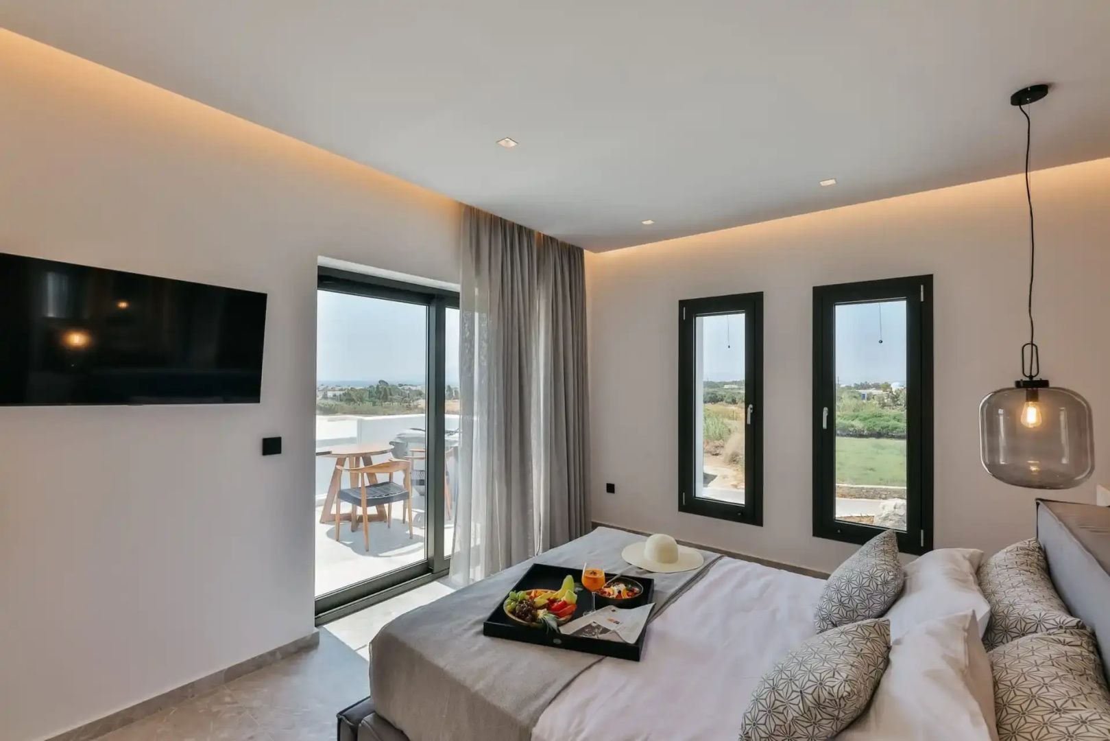Schlafzimmer mit Doppelbett, ein Tablett mit Essen darauf und Blick auf den Balkon.