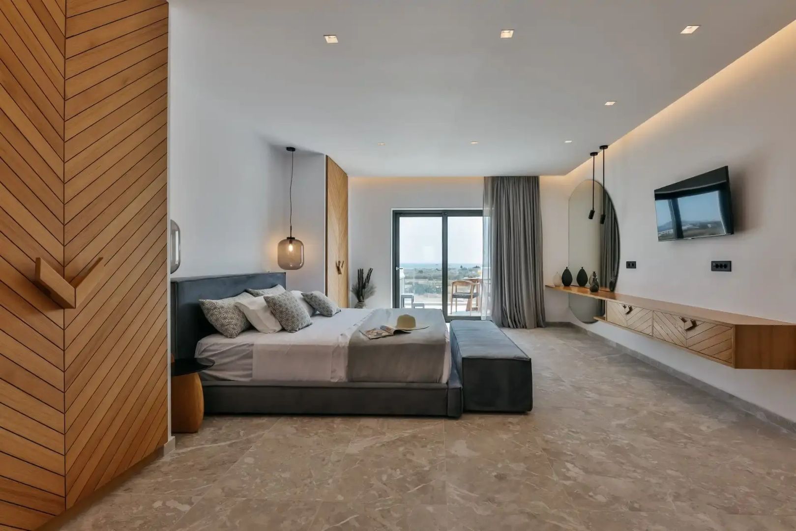 Geräumiges Schlafzimmer mit Doppelbett, Holzverkleidung und Fenstertür nach draußen.