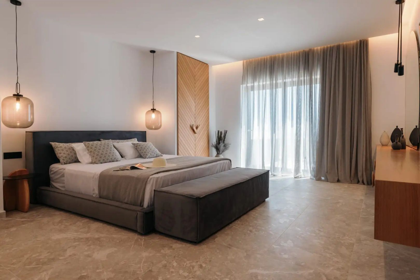 Hell gestaltetes Schlafzimmer mit Doppelbett, Bettbank und großen Fenstervorhängen.