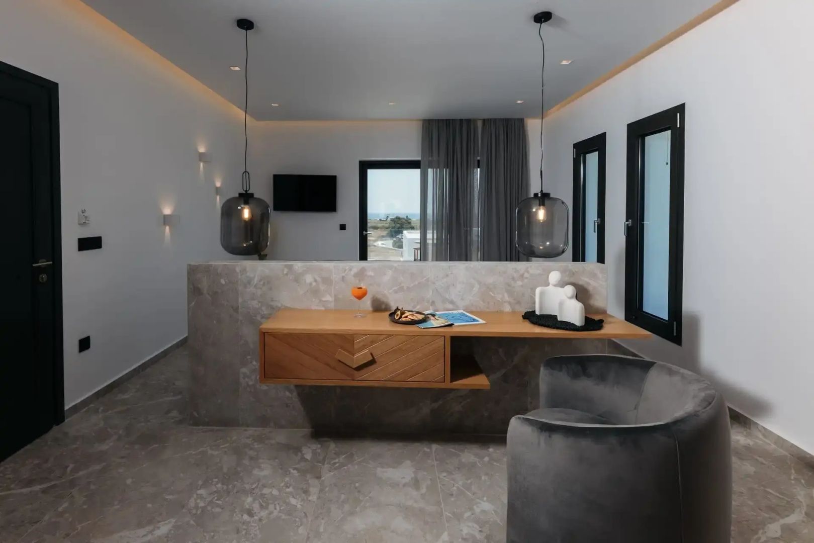 Modernes Hotelzimmer mit Schreibtisch aus Holz und grauem Sessel.