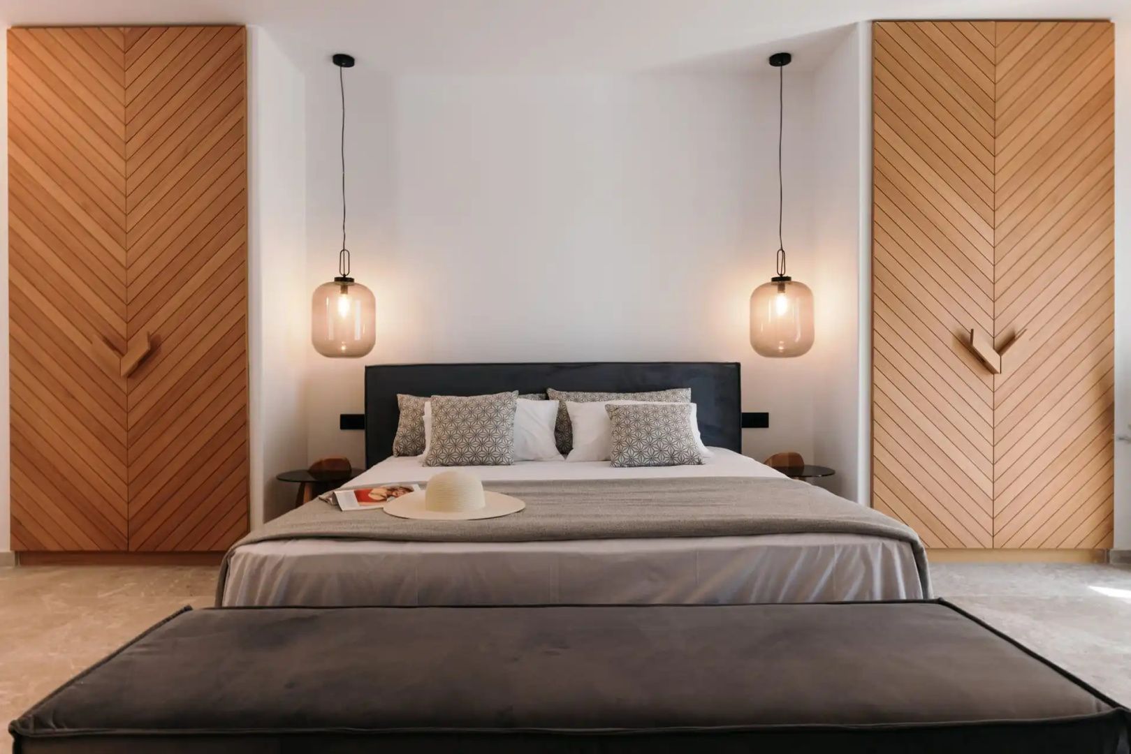 Doppelbett mit Kissen, zwei hängenden Leuchten aus Glas und seitlichen Holzschränken im Zimmer.