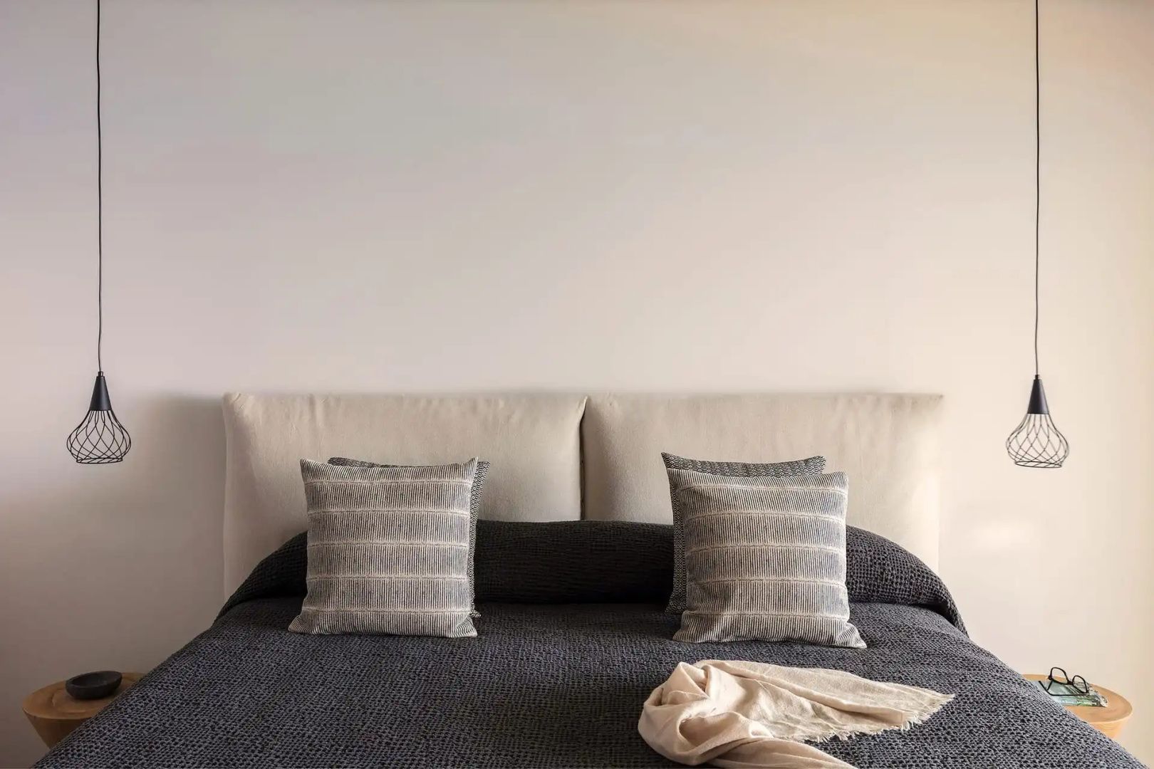 Doppelbett mit hellen Kissen, dunkler Tagesdecke und gepolstertem Kopfteil