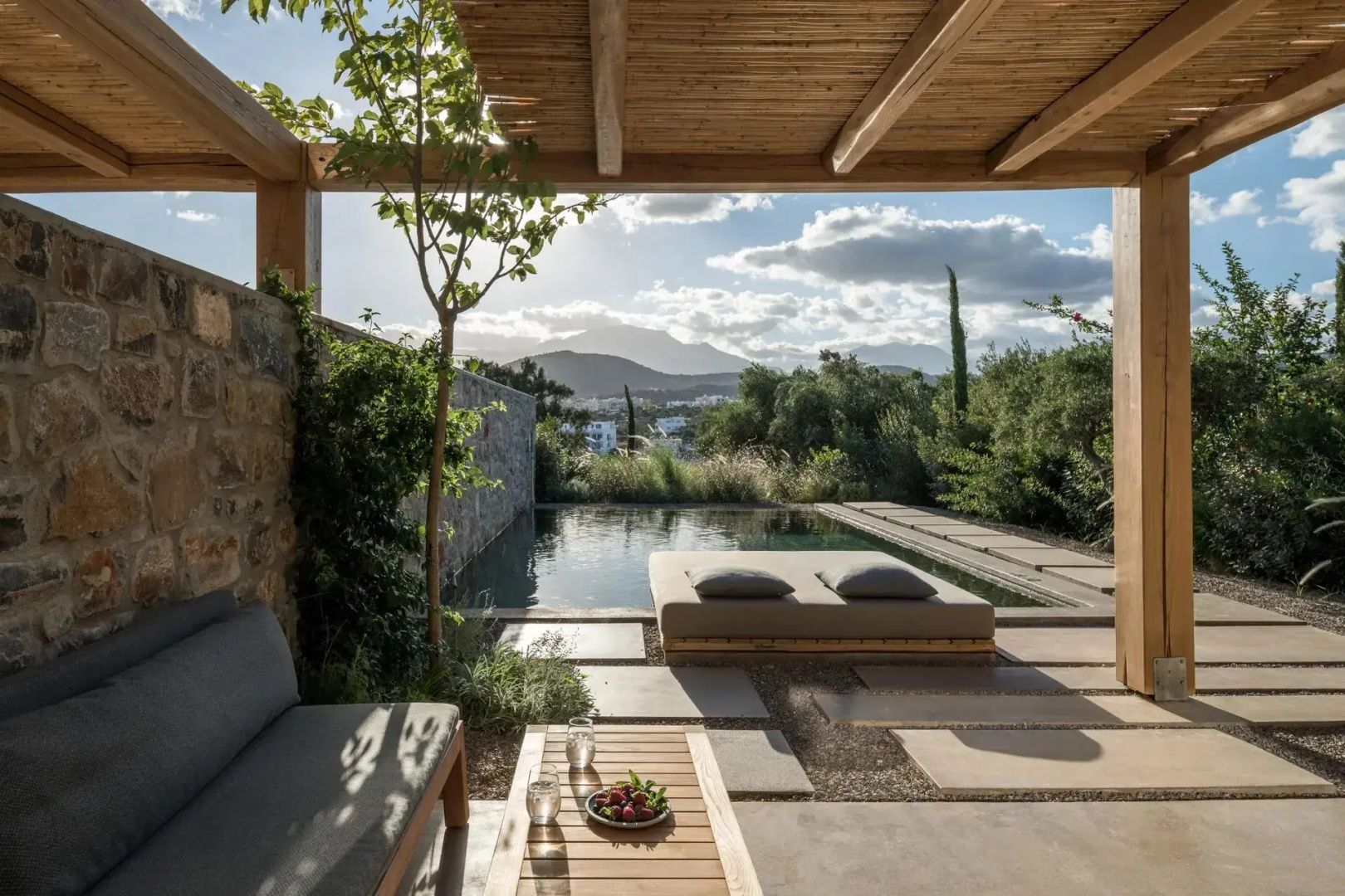 Terrasse mit Sitzgelegenheiten und Pool mit Blick auf grüne Natur und Berge.