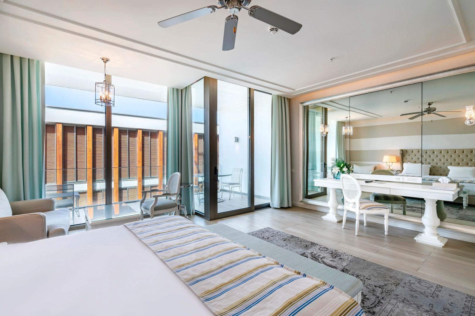 Geräumiges Schlafzimmer mit großem Doppelbett, Schreibtisch und Glasflügeltüren zum Balkon.