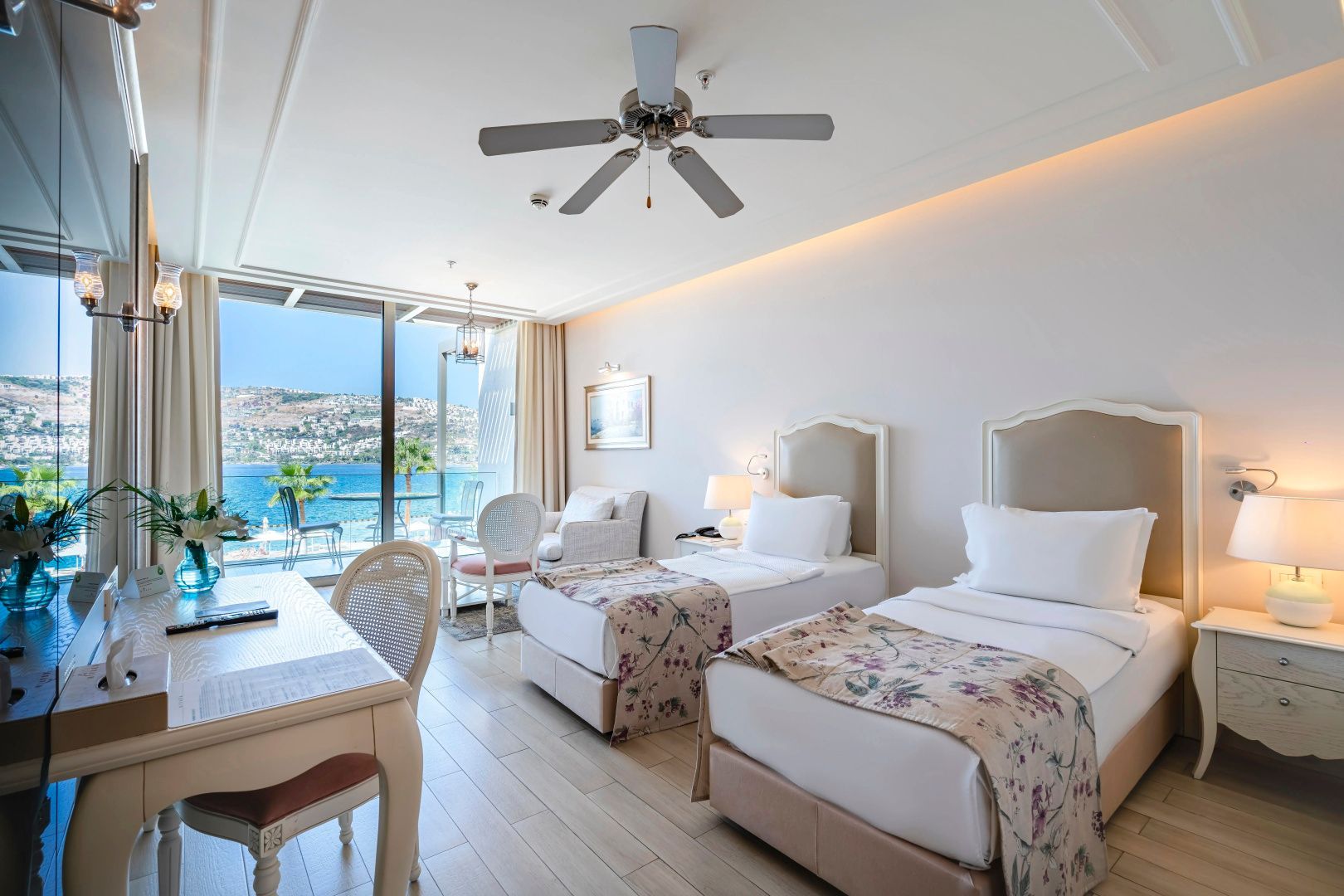 Hotelzimmer mit zwei Einzelbetten, Schreibtisch und Ausblick auf das Meer.