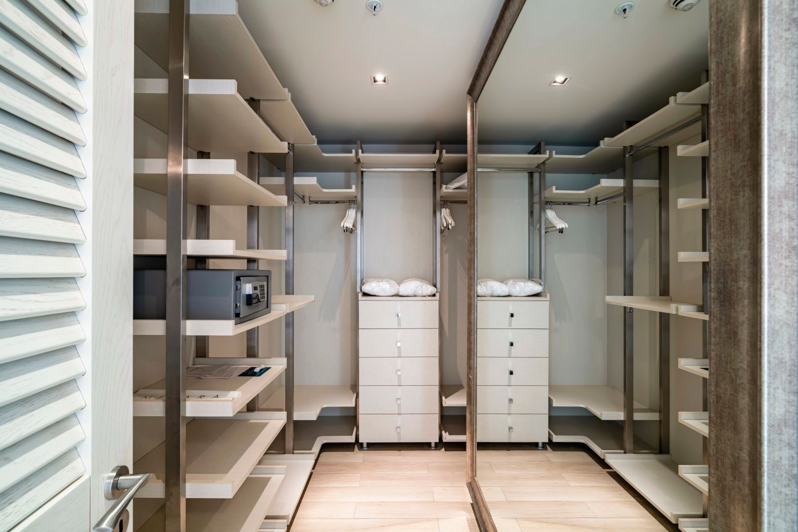 Begehbarer Kleiderschrank im Zimmer mit offenen Regalen, Schubladen und eingebautem Tresor.