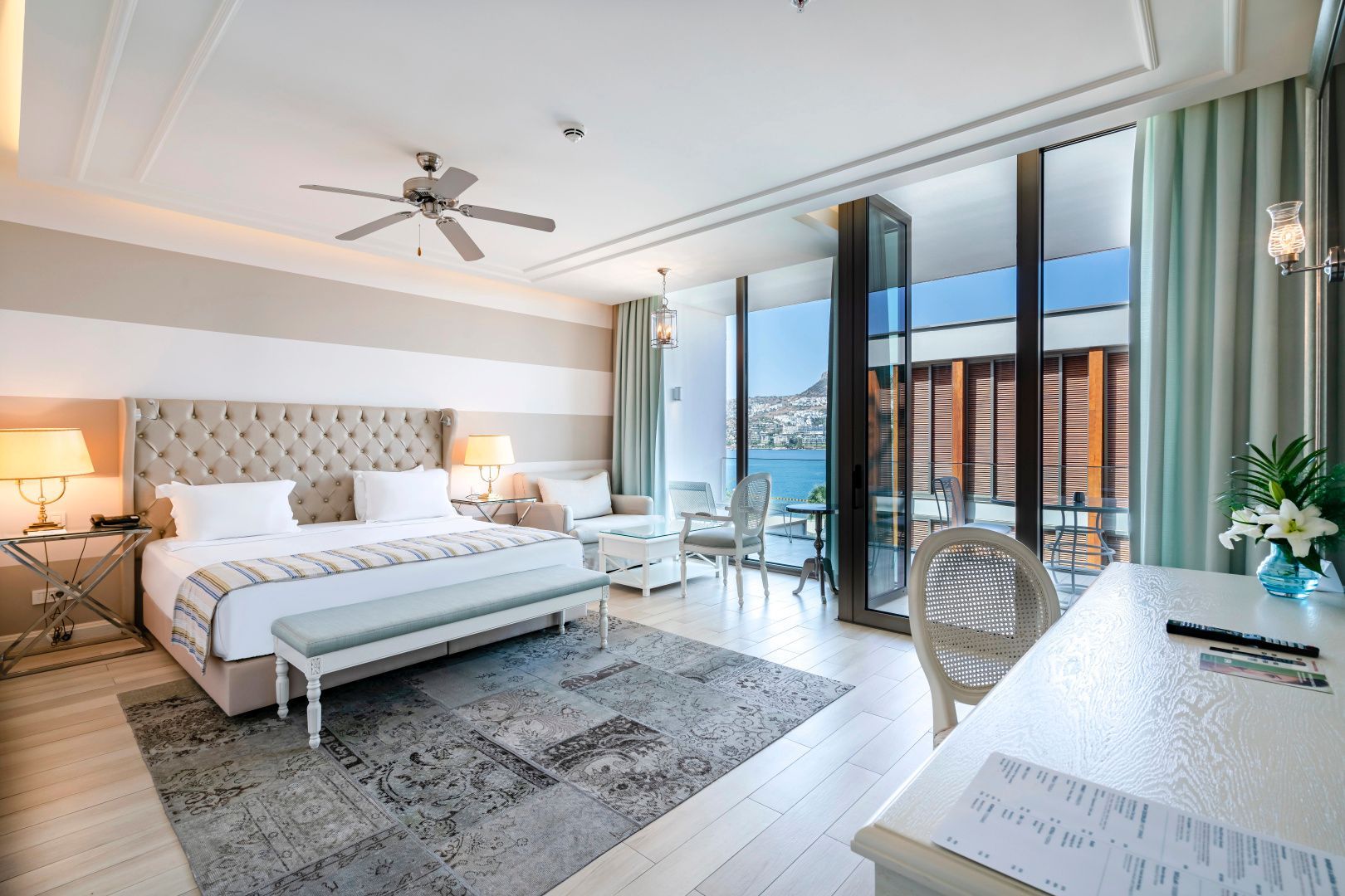 Modern eingerichtetes Schlafzimmer mit hellen Streifen an der Wand und Blick aufs Meer.