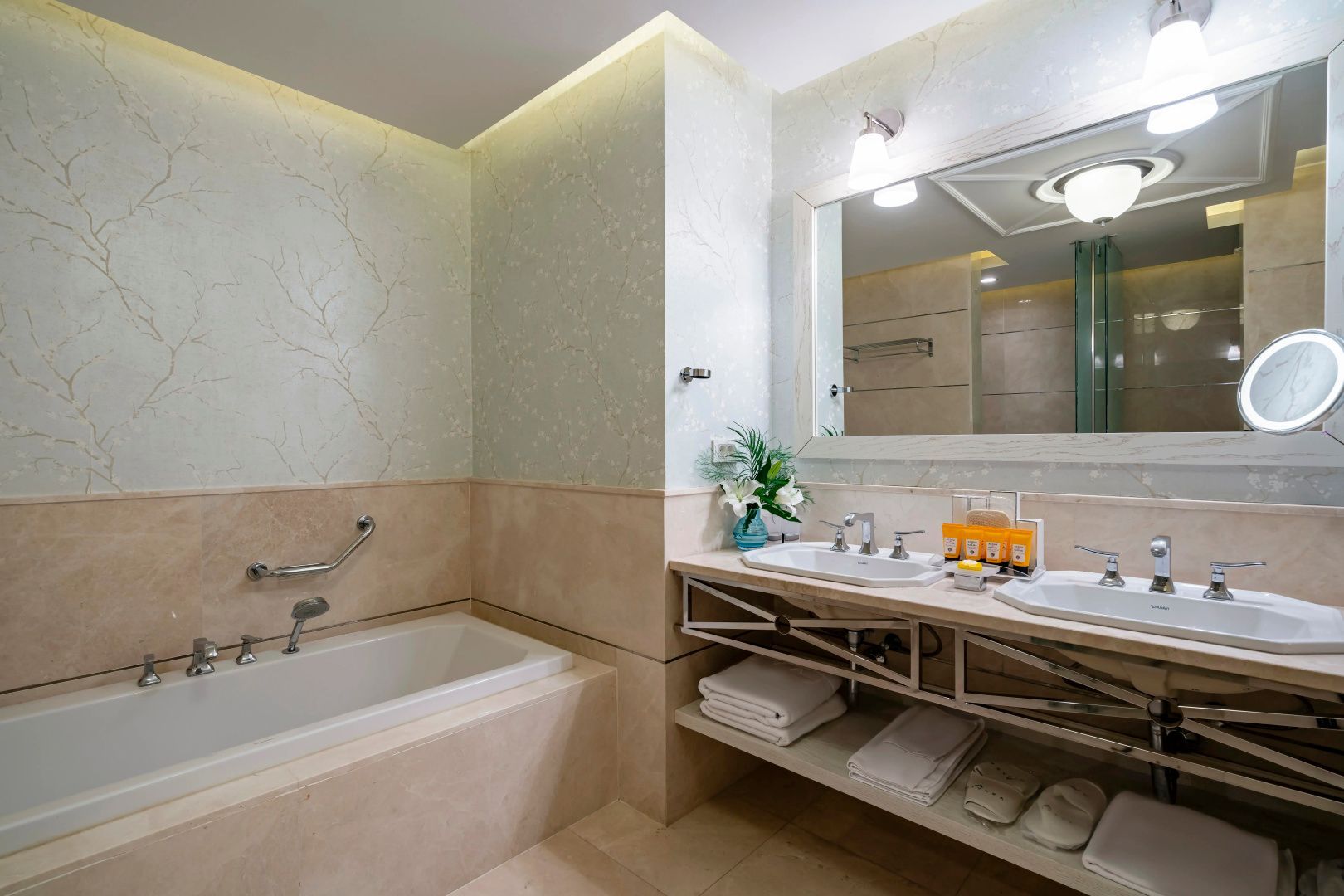 Badezimmer mit zwei Waschbecken, großem Spiegel, Handtüchern und einer Einbaubadewanne.