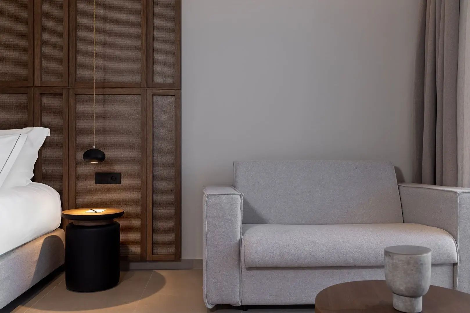 Modernes graues Sofa mit Beistelltisch und Holzverkleidung in der Suite.