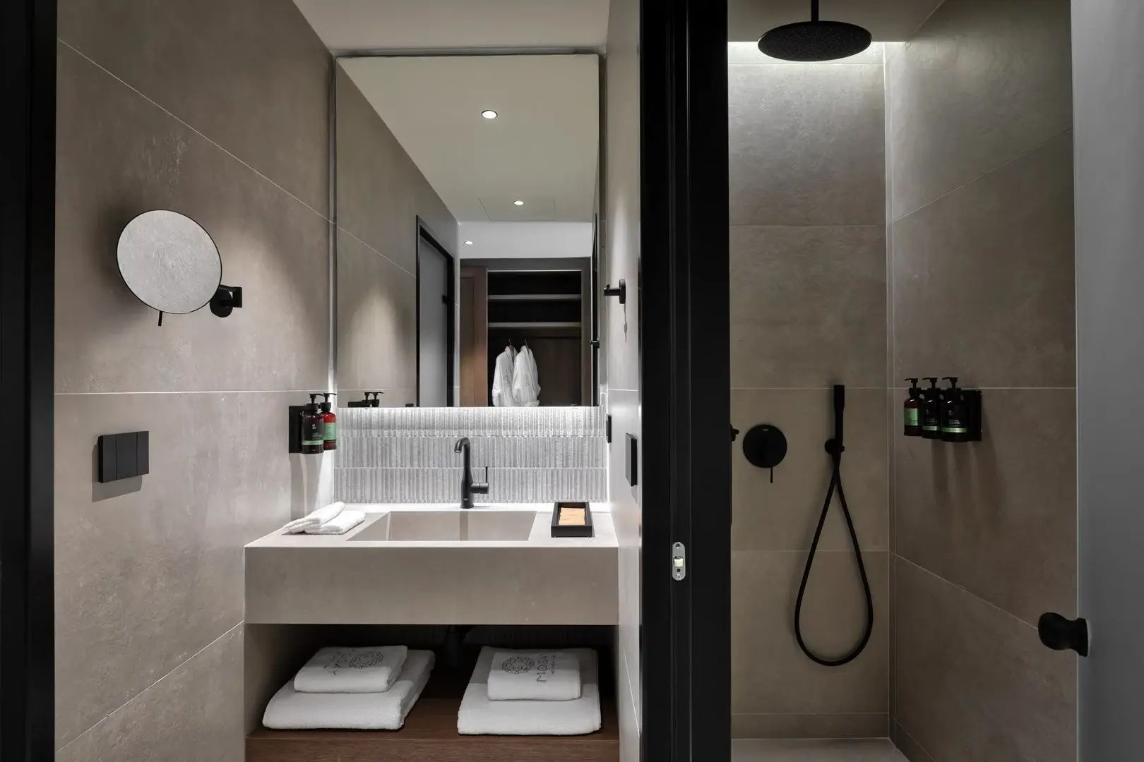 Modernes Badezimmer mit beleuchtetem Spiegel, grauem Waschtisch und Dusche rechts.