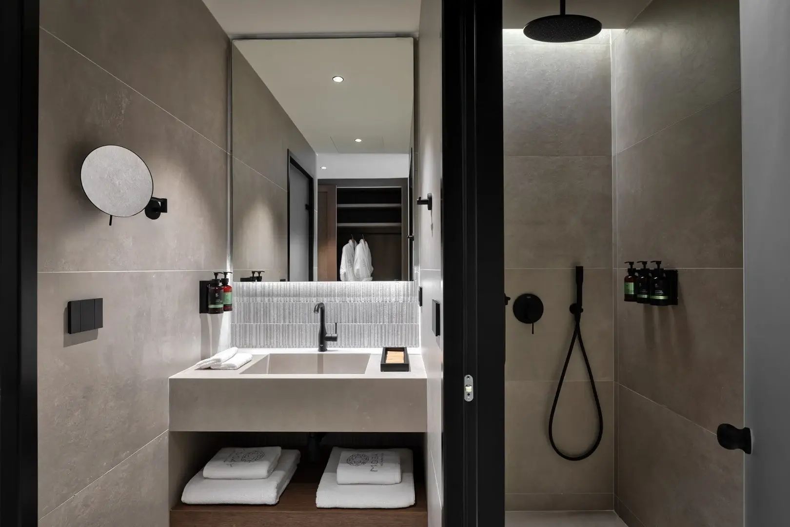Modernes Badezimmer mit beleuchtetem Spiegel, Waschtisch und begehbarer Dusche.