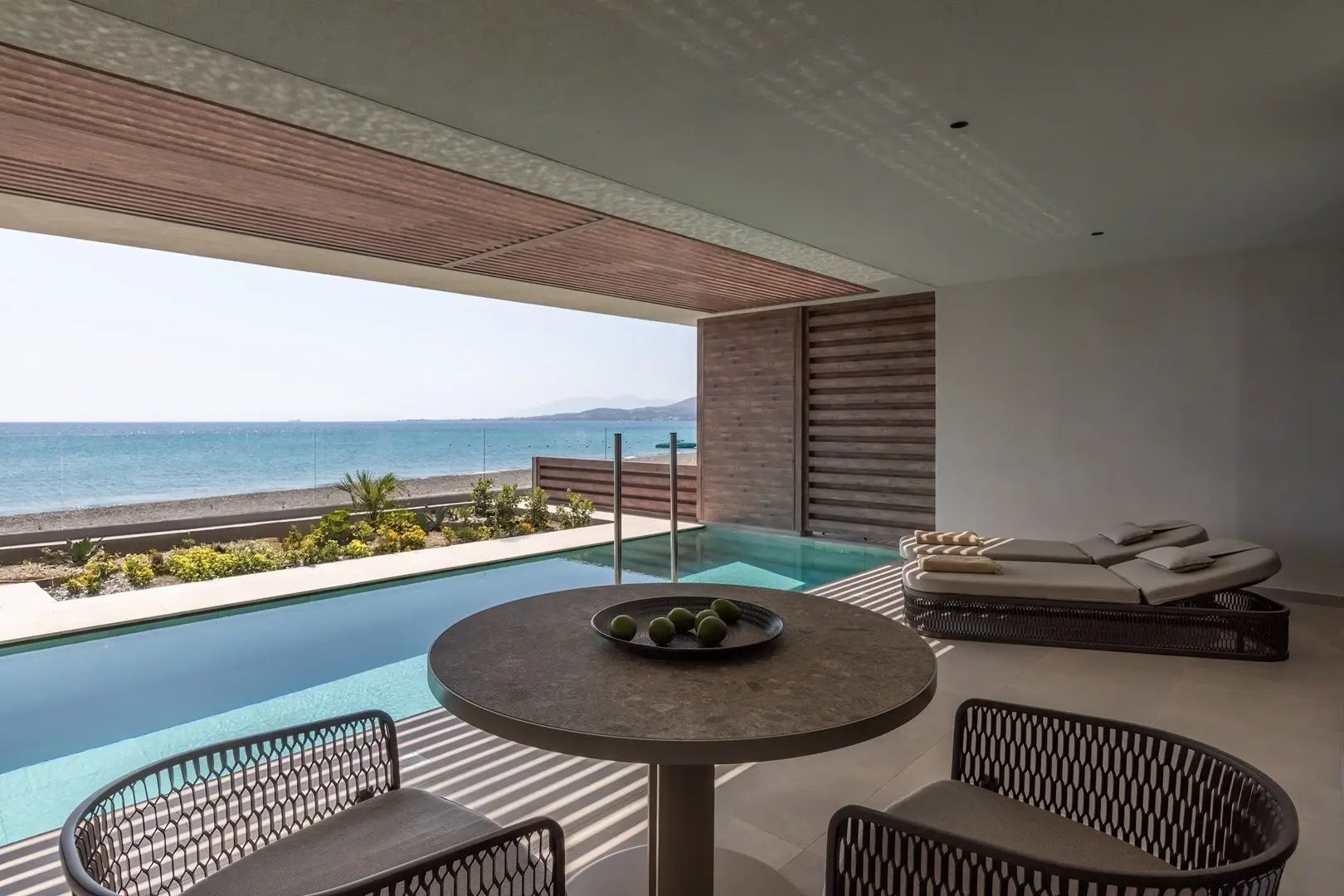 Runder Esstisch auf einer Terrasse mit direktem Blick auf den Pool und das Meer.
