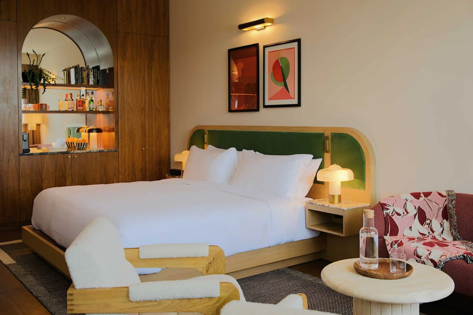 Doppelbett mit weißer Bettwäsche, grünem Kopfteil und Nachttischlampen im Hotelzimmer.