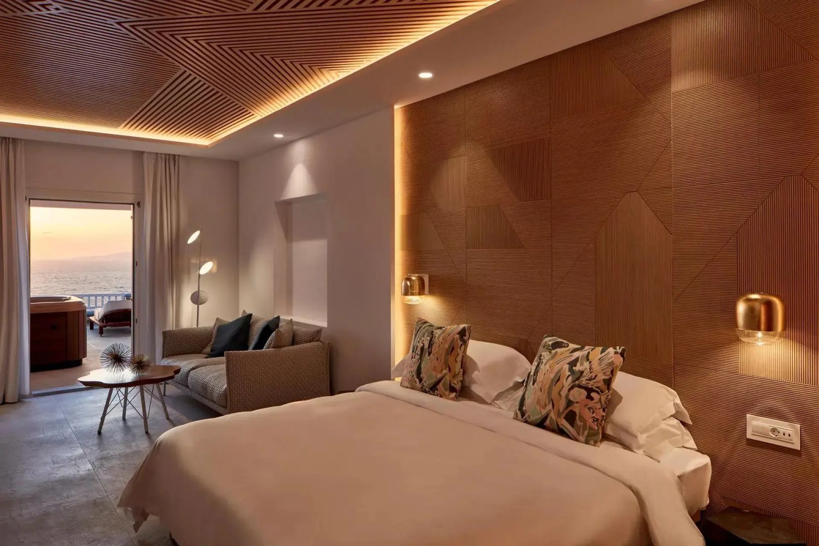 Hotelzimmer mit strukturierter Holzdecke, indirekter Beleuchtung, Doppelbett und Sofa.