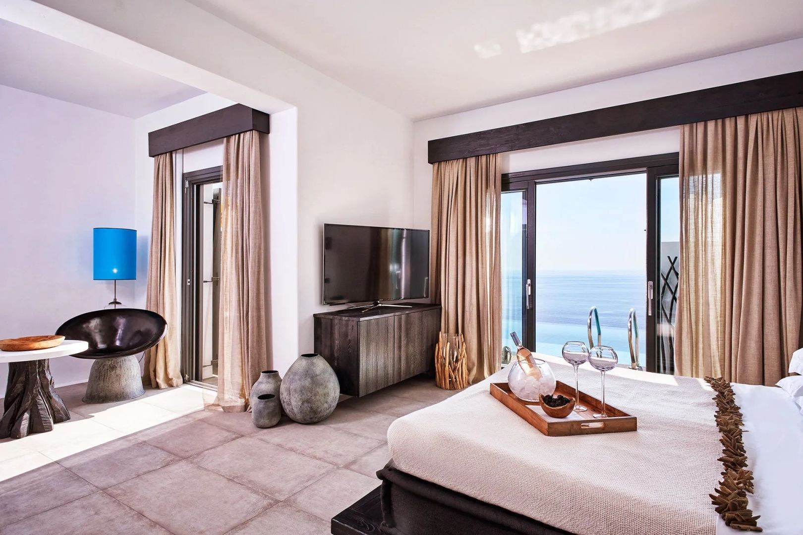 Schlafbereich einer Suite mit Blick auf das Meer durch eine große Glasfront.
