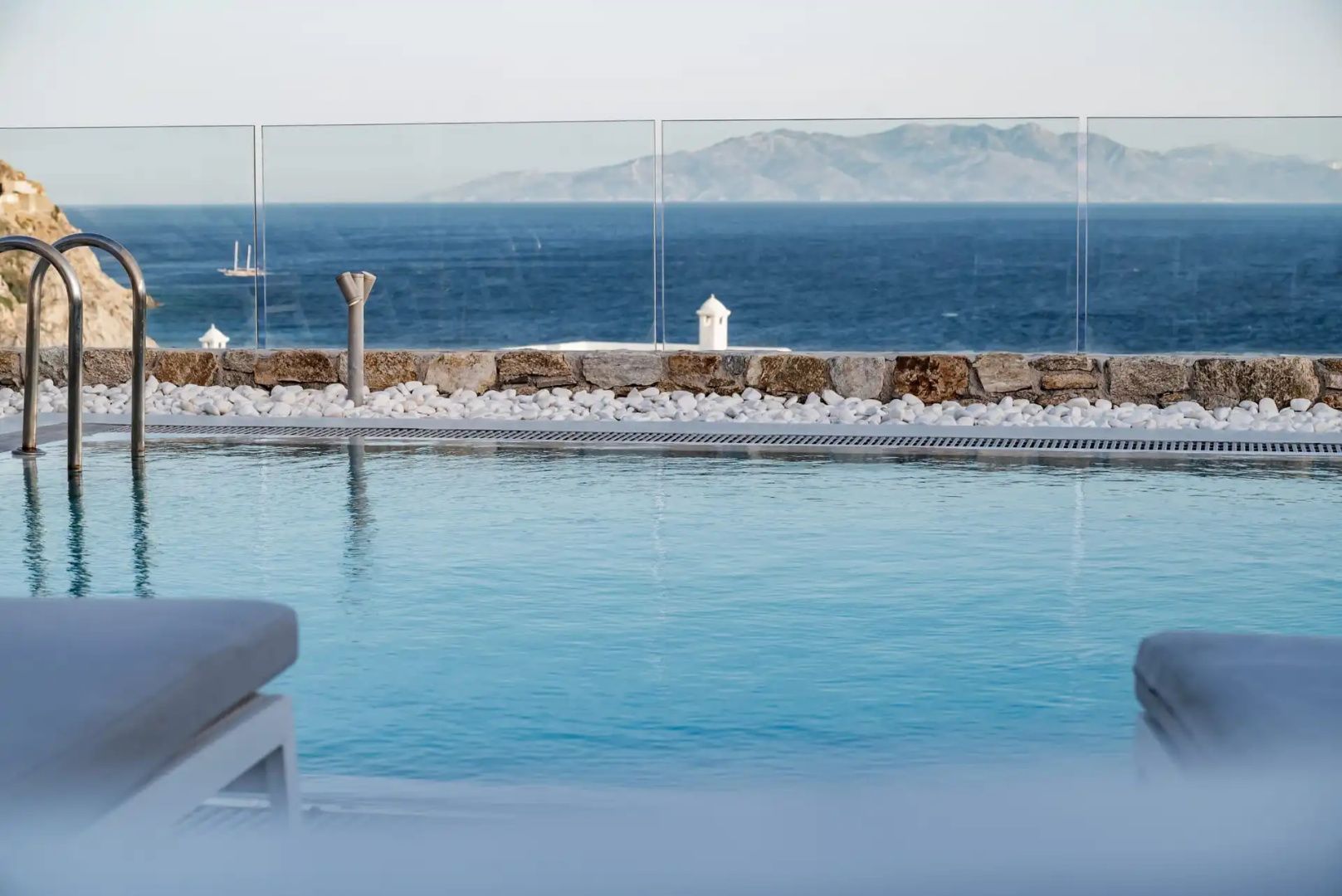 Außenpool mit einer Glasabsperrung und Blick auf das Meer sowie entfernte Inseln.