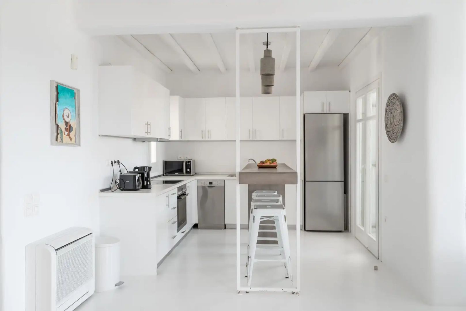 Moderne weiße Küche mit Kücheninsel, Barhockern und Edelstahlkühlschrank.