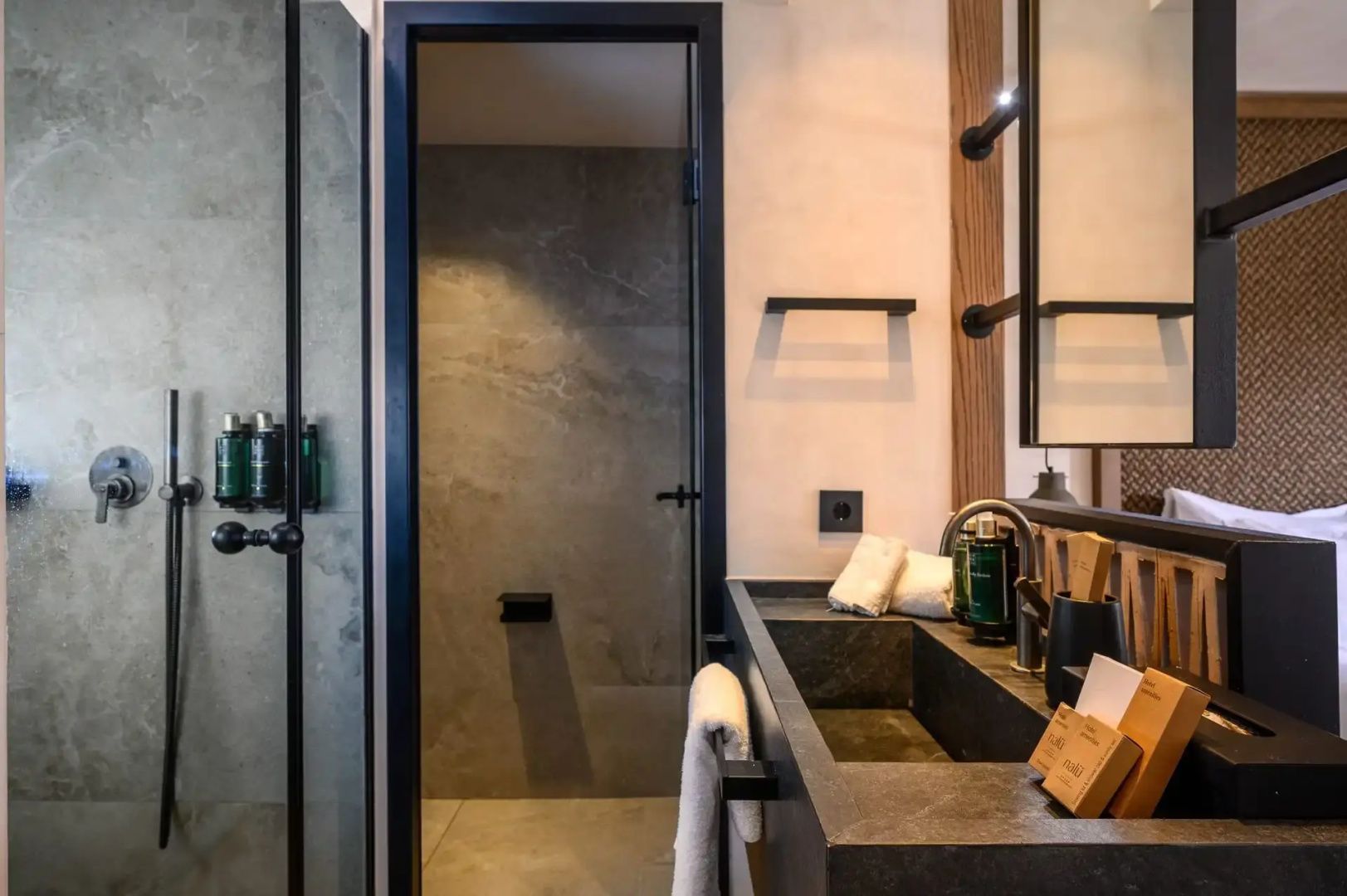Badezimmerbereich mit schwarzem Waschbecken, Handtüchern und einer angrenzenden Dusche.