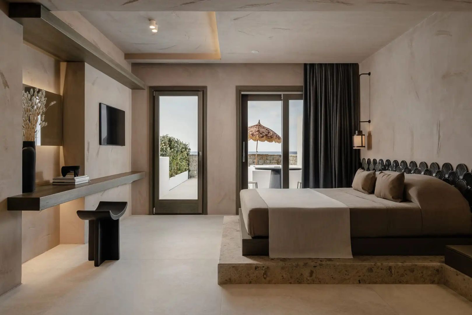 Geräumiges Schlafzimmer mit Doppelbett, Wandfernseher und Zugang zur Terrasse.