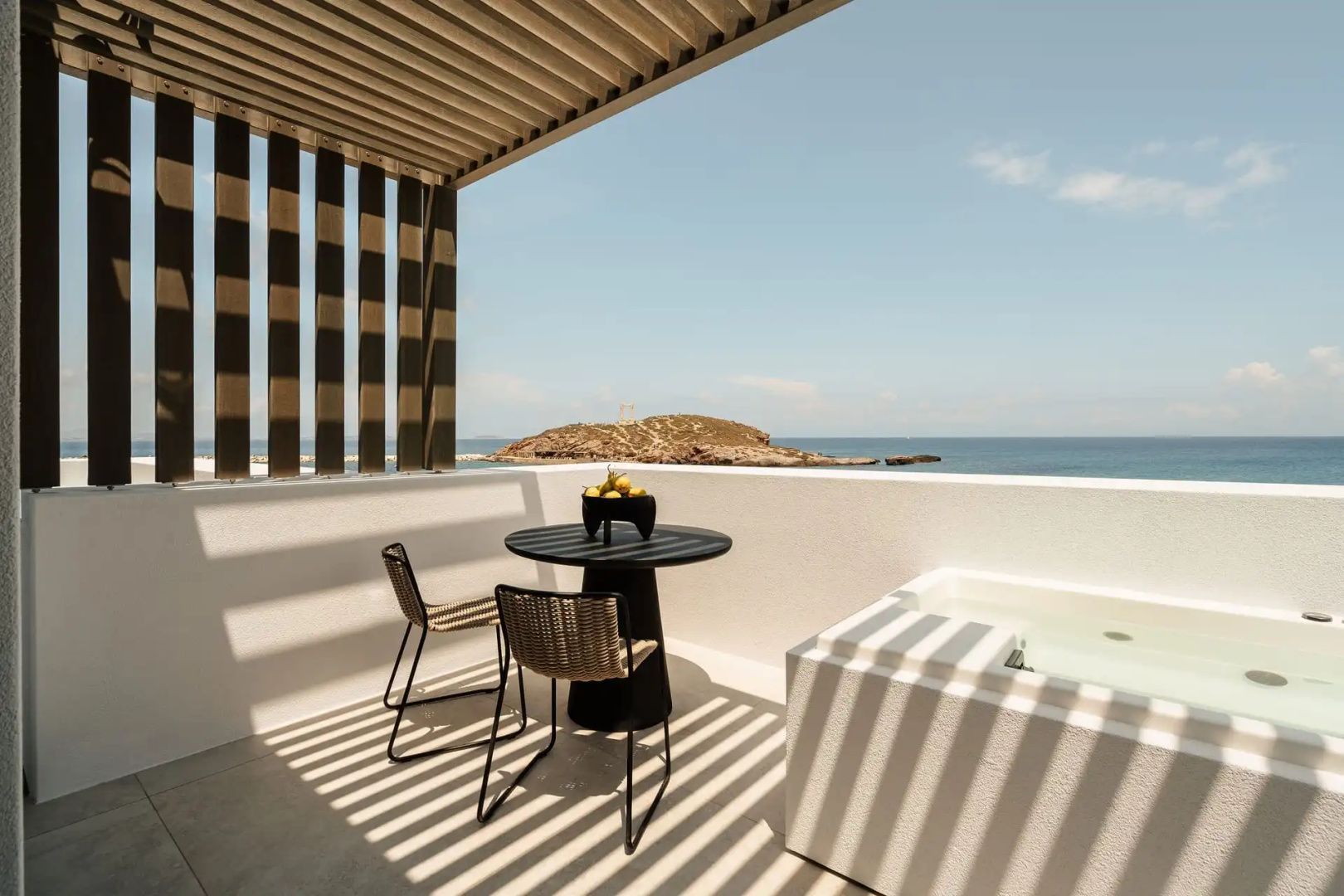 Sonnige Terrasse mit Whirlpool, Sitzgruppe und Blick auf die Meeresbucht und Inseln.