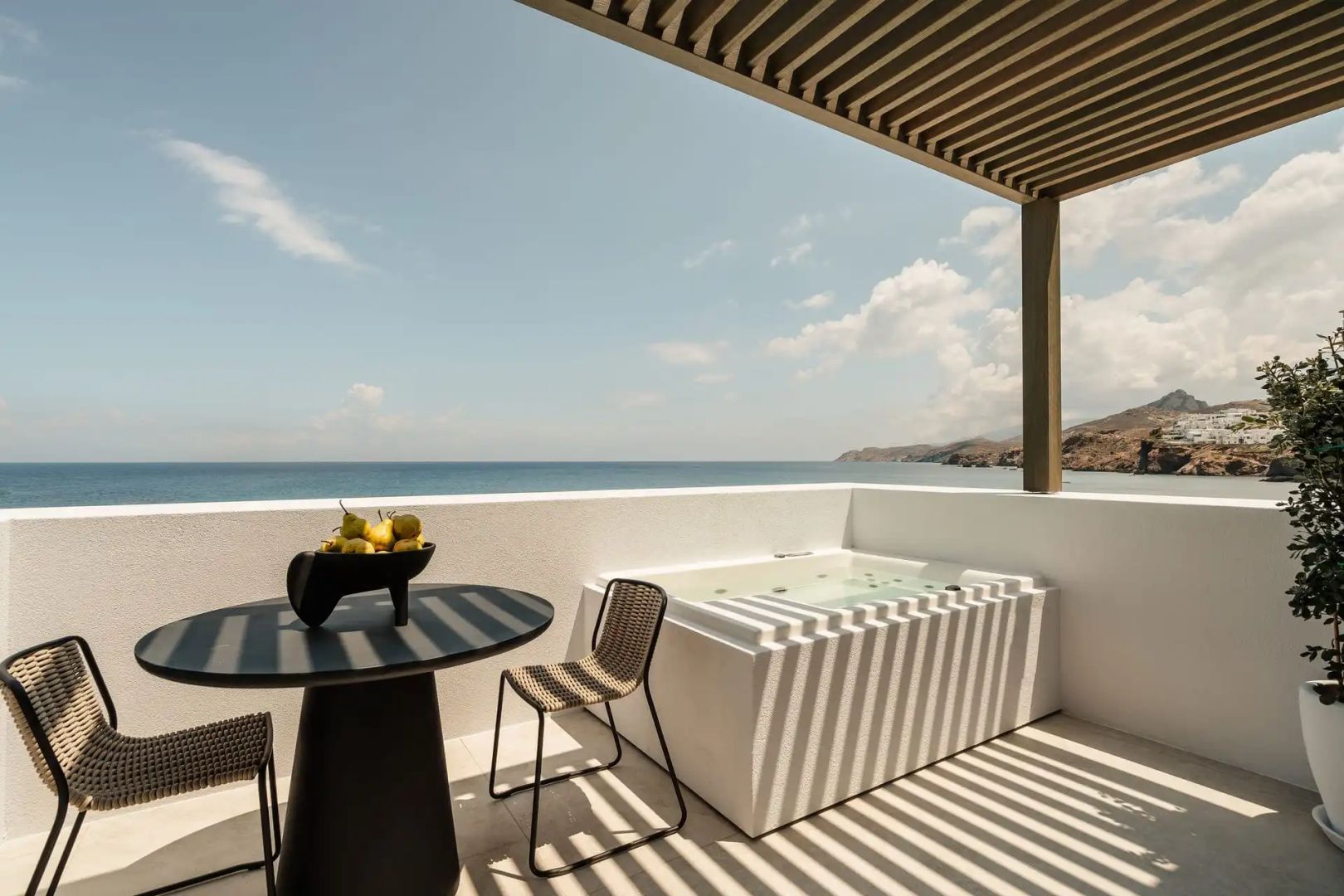 Balkon mit Whirlpool, Esstisch und Holzüberdachung mit Blick auf das offene Meer.