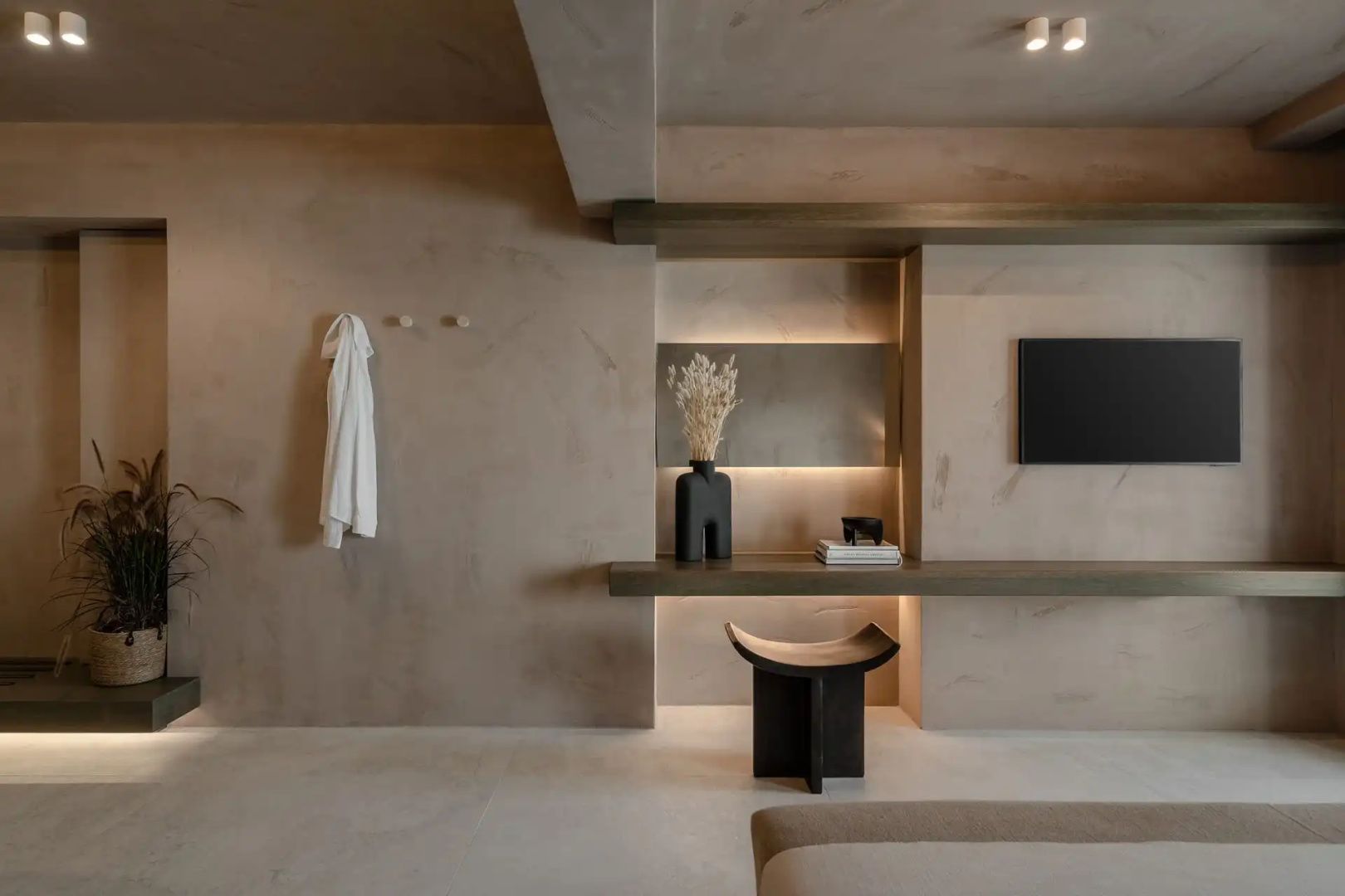 Modernes Zimmer mit erdigen Wänden, Holzschreibtisch, Fernseher und Dekoration.